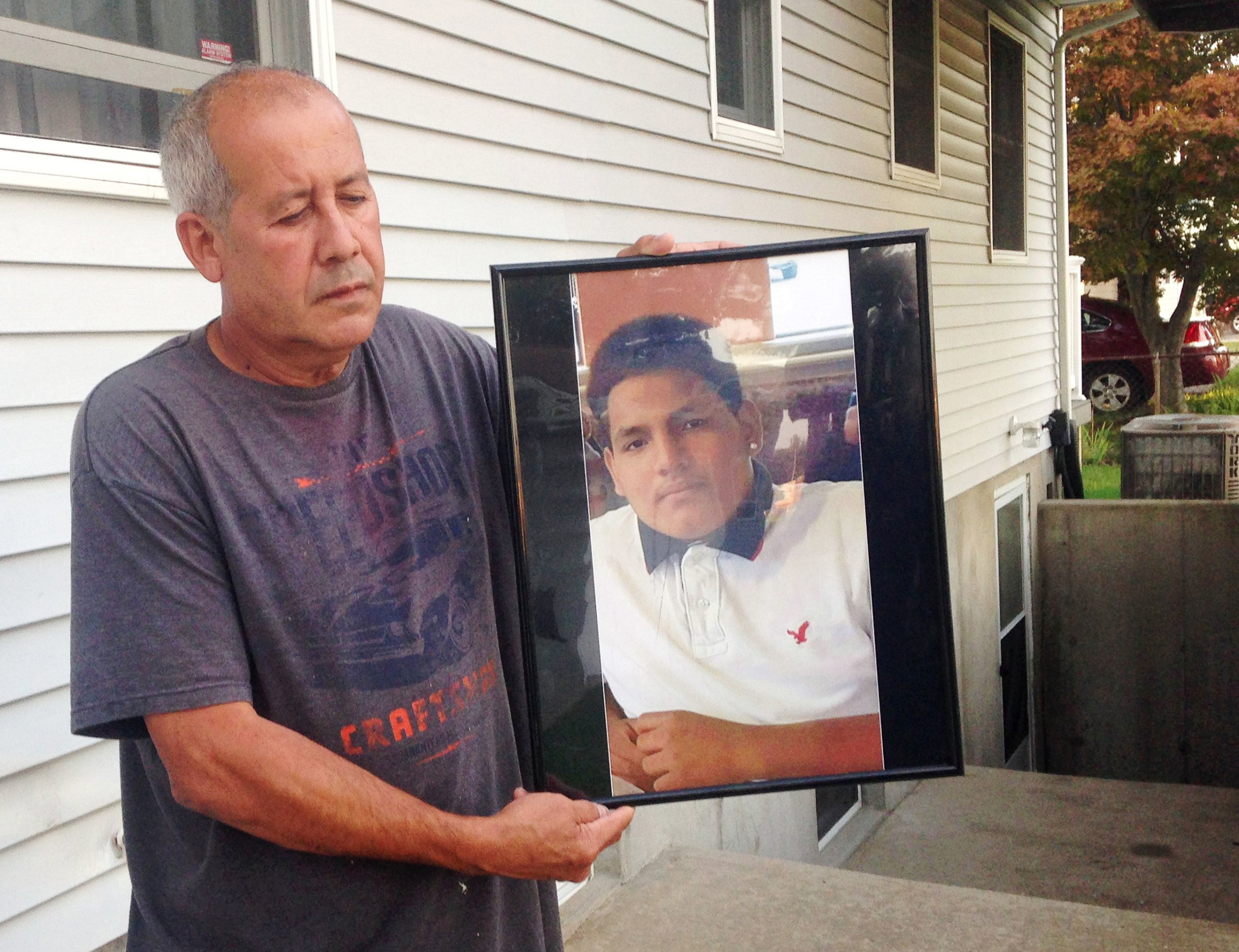 In this Sept. 27, 2016 photo, Abraham Chaparro, holds a photograph of his murdered stepson, Miguel Garcia-Moran, outside his home in Brentwood, N.Y. The remains of Garcia-Moran, who was reported missing in February, were found in September. Multiple teenagers from the same Long Island high school have been found dead and while police suspect all the deaths are related to gang violence, they are releasing few details. (AP Photo/Claudia Torrens)