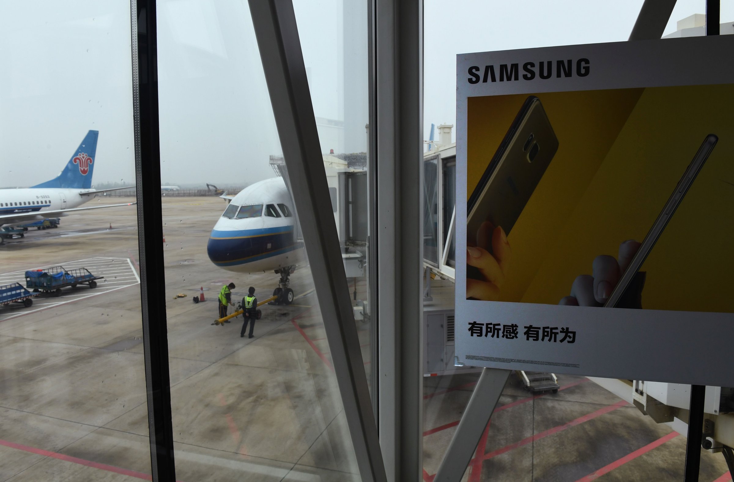 An advertisement for the Samsung Galaxy Note 7 smartphone is seen on an air bridge leading to a plane at the airport in Wuhan, in China's central Hubei province on October 2, 2016. Signs at the Wuhan airport check-in counters warn passengers not to switch on or charge Note 7 smartphones on the plane and ban them from check-in luggage. The warnings follow Samsung's recall of Note 7 phones after cases of batteries catching fire were reported in the US. / AFP PHOTO / GREG BAKERGREG BAKER/AFP/Getty Images