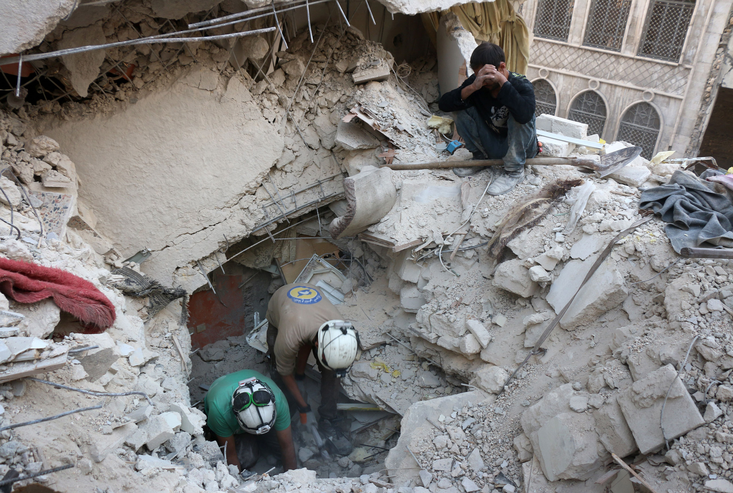 Syrian civil defence volunteers, known as the White Helmets, search for victims amid the rubble of destroyed buildings following a government forces air strike on the rebel-held neighborhood of Bustan al-Basha in Aleppo, on Oct. 4, 2016. (Thaer Mohammed—AFP/Getty Images)