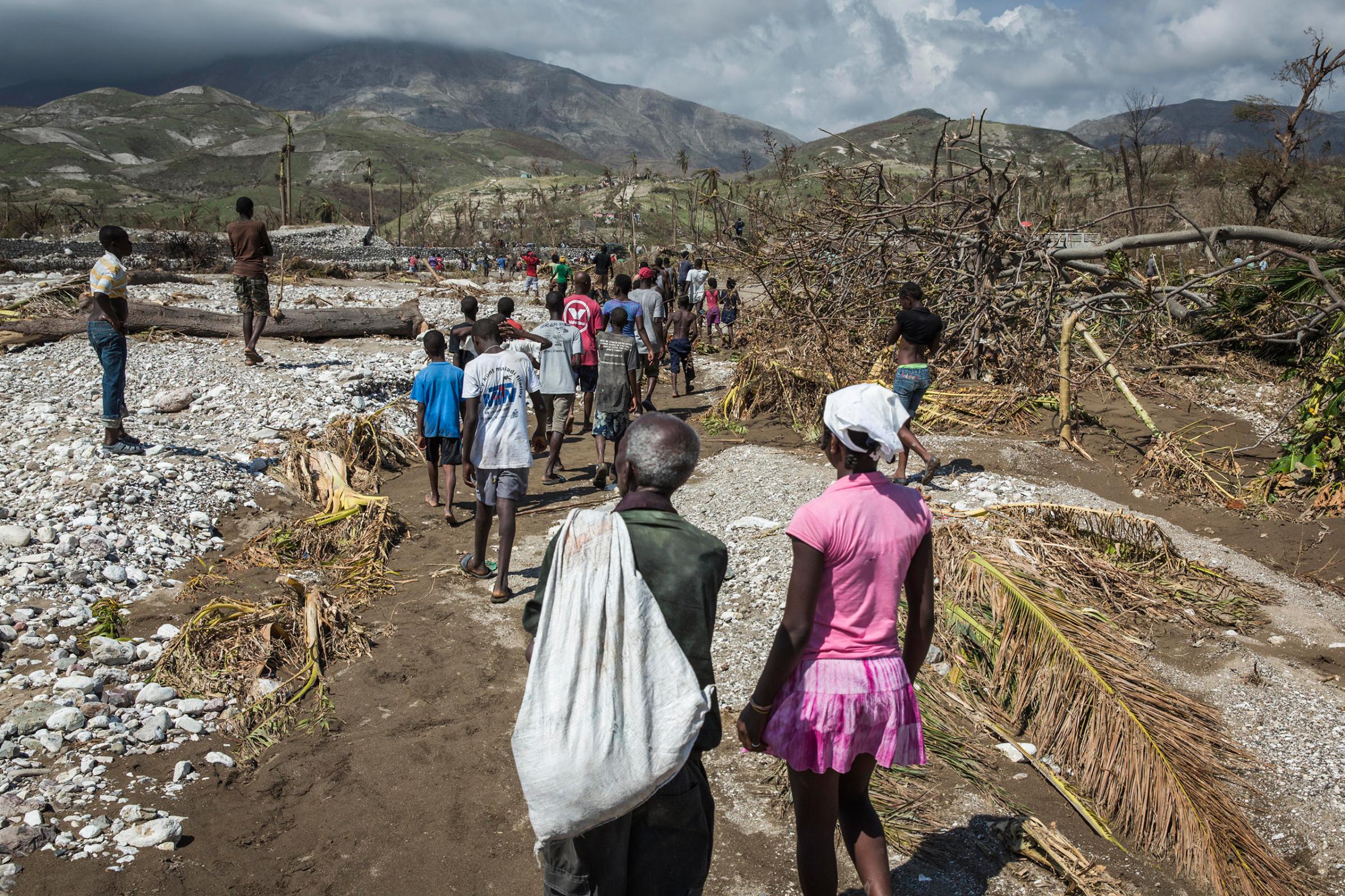 People walk along a path to the river in order to cross through the water on foot as the bridge has collapsed in Roche-a-Bateau, southwestern Haiti, on Oct. 8, 2016. Many Haitians originally from the south of the country are returning home to visit family and help in the recovery from the impact of Hurricane Matthew.