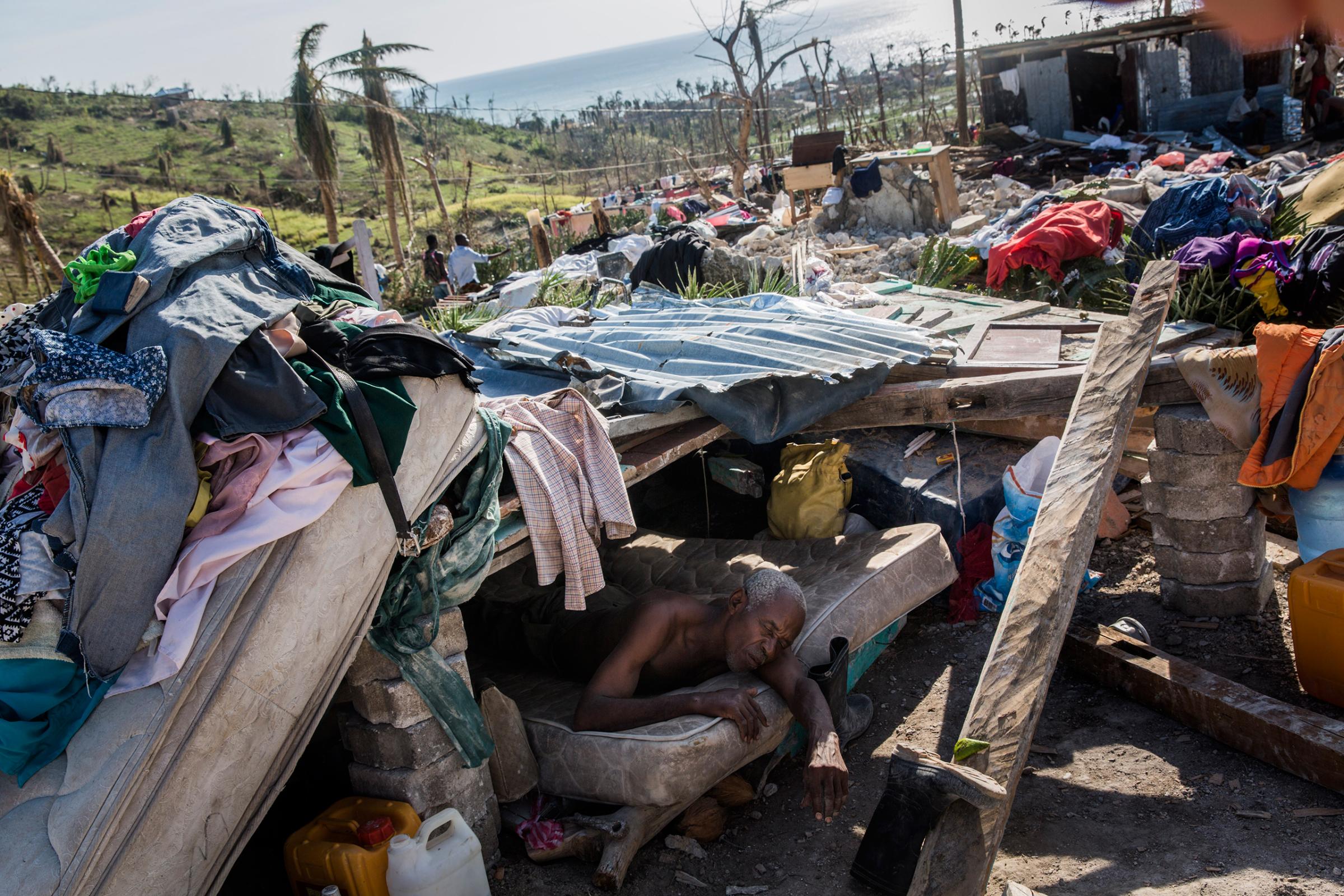 A man who is too ill to walk rests in a makeshift shelter on the site of his destroyed home in Roche-a-Bateau, southwestern Haiti, on Oct. 8, 2016.