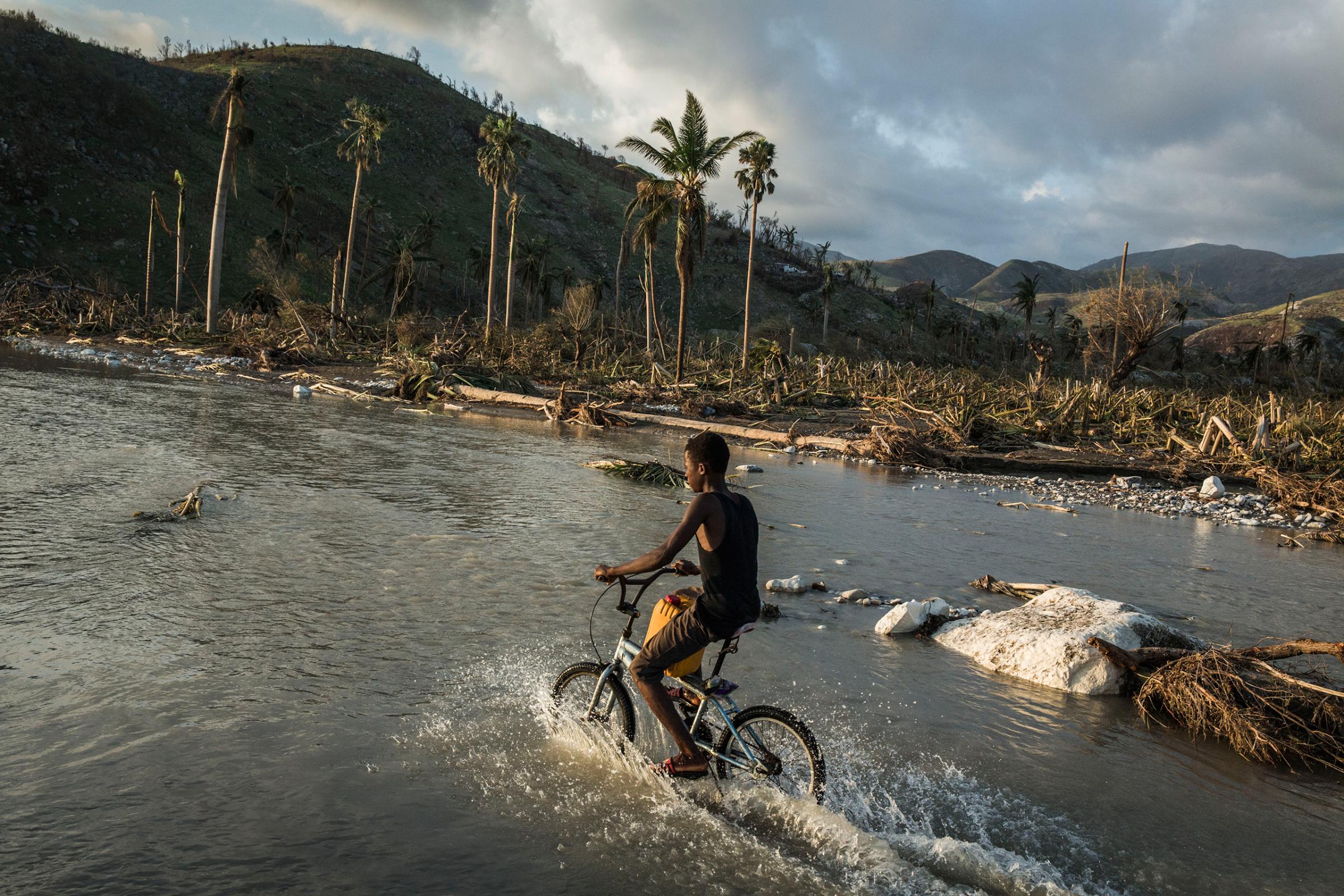A boy rides his bicycle along a flooded road in a devastated area near Port Salut, in southwestern Haiti, on Oct. 8, 2016.