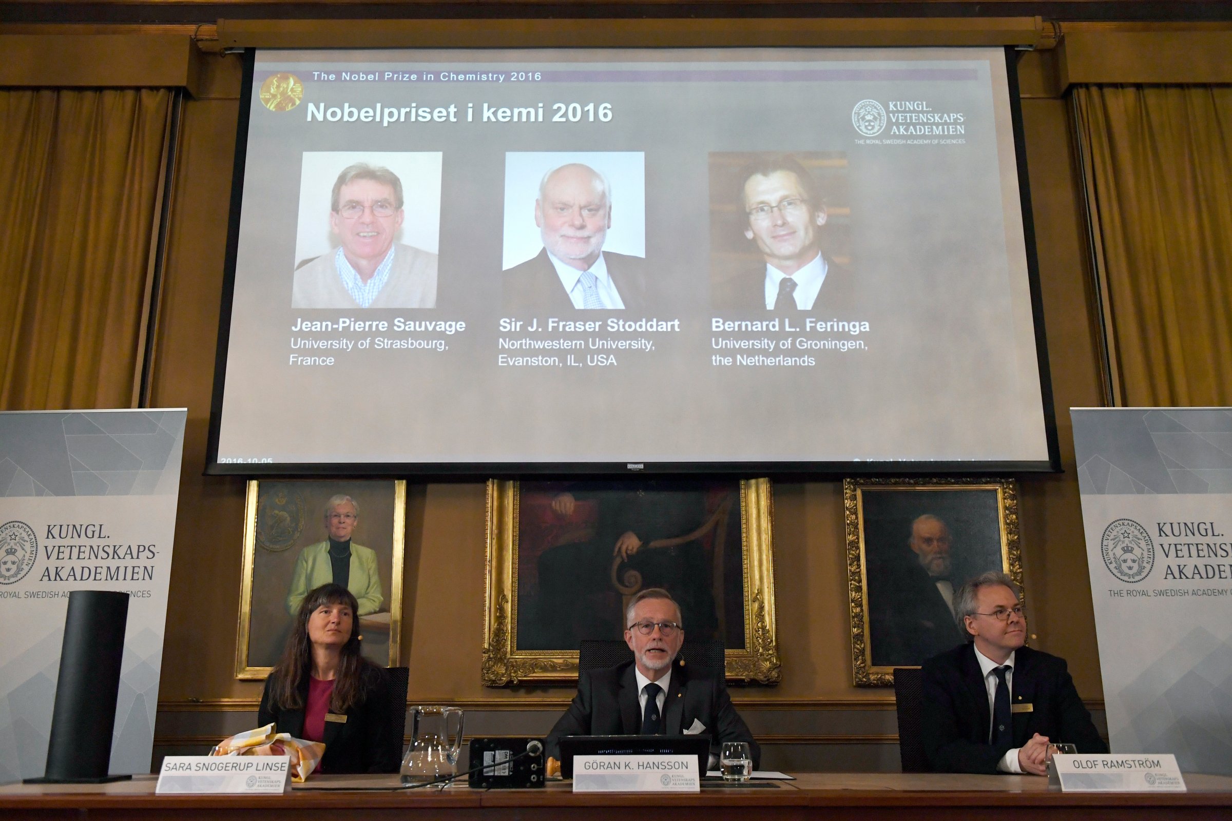The Royal Academy of Sciences members, from left to right, Professor Sara Snogerup Linse, Professor Goran K Hansson and Professor Olof Ramstrom present the 2016 Nobel Chemistry Prize at the Royal Swedish Academy of Sciences, in Stockholm, Sweden, Wednesday, Oct. 5, 2016. Jean-Pierre Sauvage, Fraser Stoddart and Bernard Feringa have been awarded the Nobel chemistry prize. (Henrik Montgomery /TT via AP)