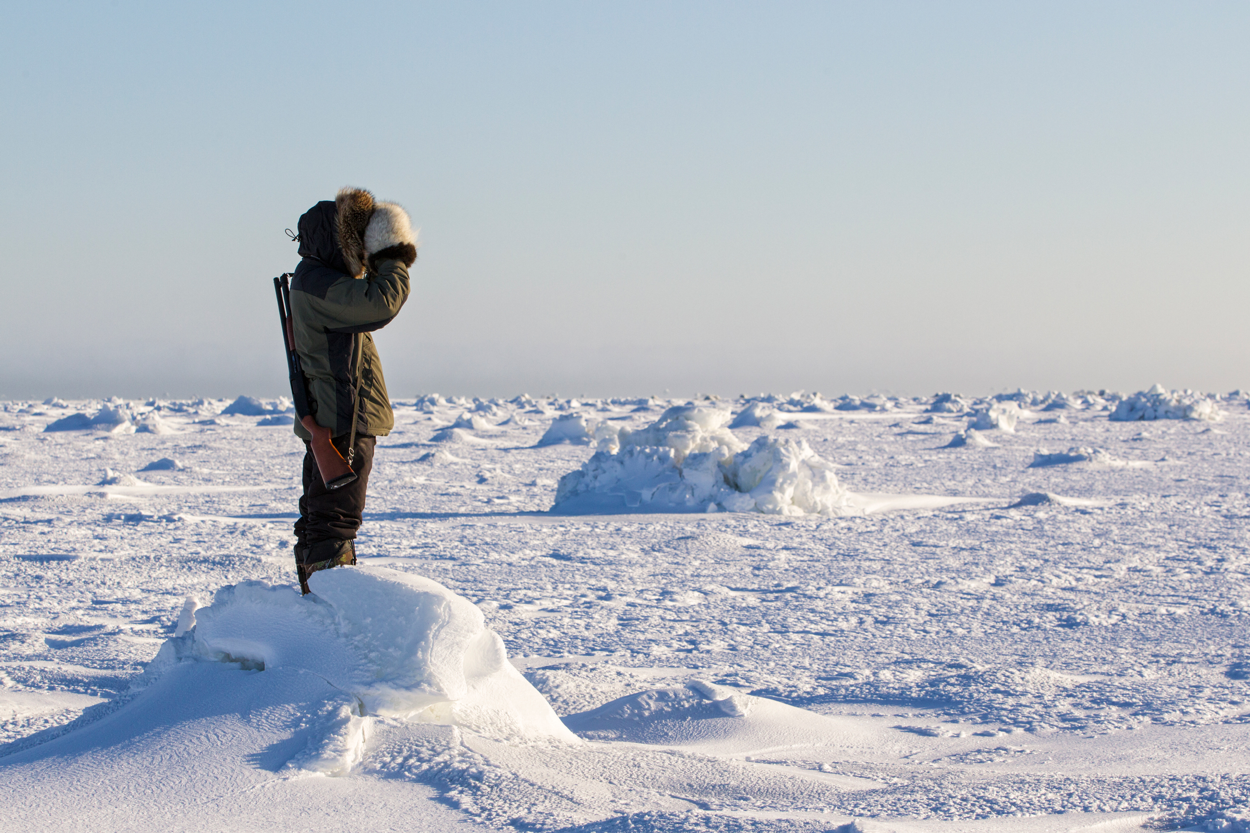 Inuit man scanning ice for polar bears, west coast Hudson Bay, south of Arviat, Nunavut, Canada