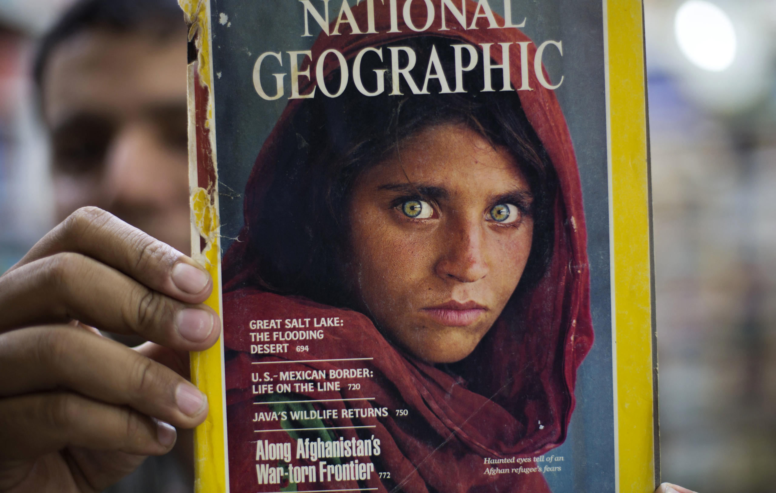 Pakistan's Inam Khan, owner of a book shop shows a copy of a magazine  with the photograph of Afghan refugee woman Sharbat Gulla, from his rare collection in Islamabad, Pakistan, on, Oct. 26, 2016. A Pakistani investigator says the police have arrested National Geographic's famed green-eyed 'Afghan Girl' for having a fake Pakistani identity card. (B.K. Bangash—AP)
