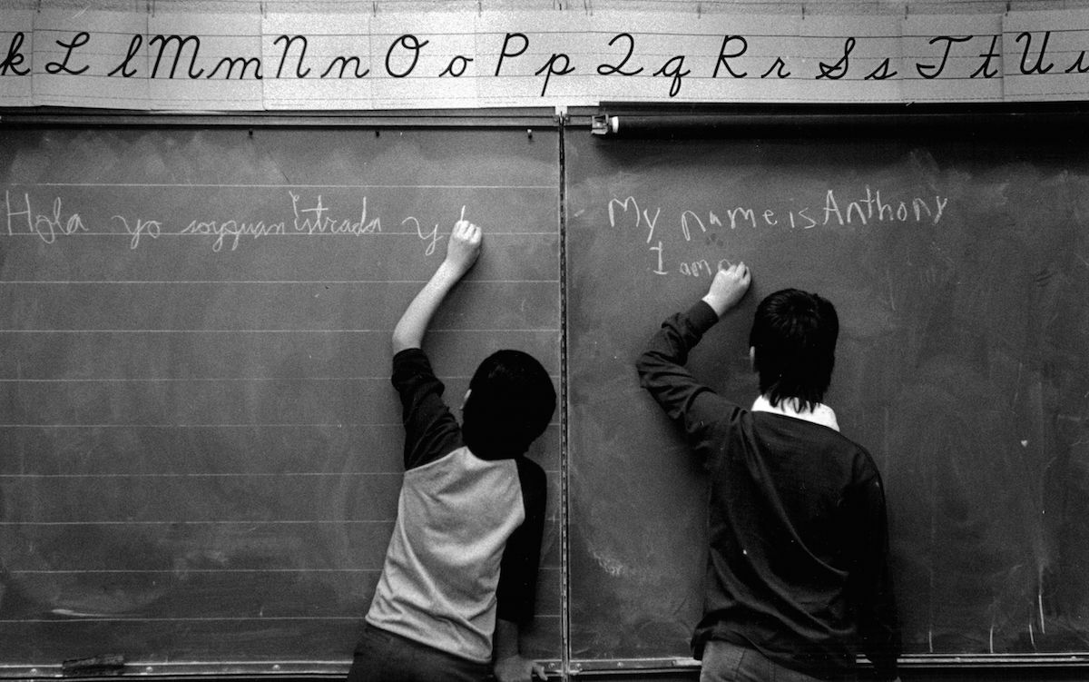 Scene from a bilingual classroom in Denver in 1987: Juan Estrada (11) and Anthony Vasquez (9) write an introduction to themselves on the blackboard in the language that each of them knows best. (Lyn Alweis—Denver Post / Getty Images)