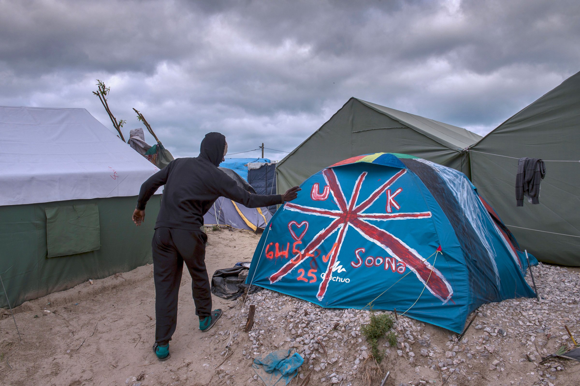 A Sudanese man stands near a tent painted with the British flag at the "Jungle" migrant camp in Calais on Oct. 12, 2016.