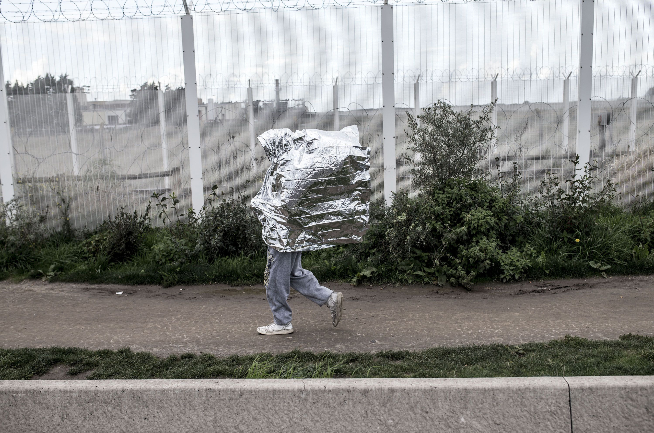 A resident of the refugee camp called 'The Jungle' walking with a survival blanket in Calais, France, on Oct. 17, 2016. (Barbaros Kayan—MOKU/SIPA/AP)