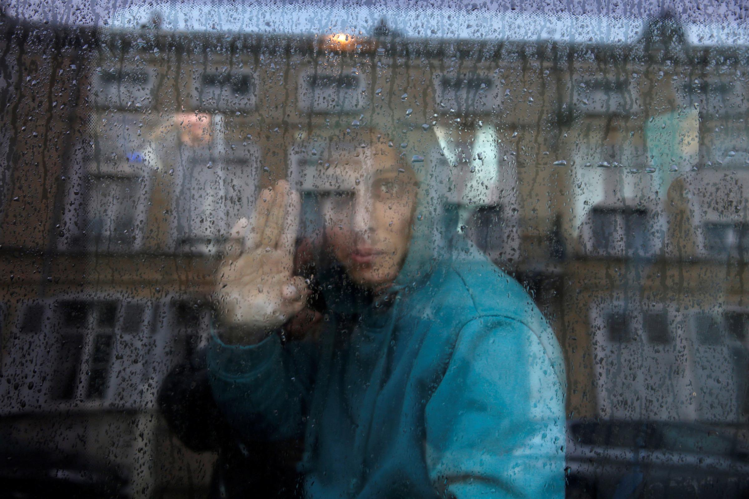 An Afghan adolescent migrant waves from a van as he departs with six others from the emergency shelter for minors in Saint Omer, France as they leave for Britain October 18, 2016. REUTERS/Pascal Rossignol TPX IMAGES OF THE DAY - RTX2PBMX