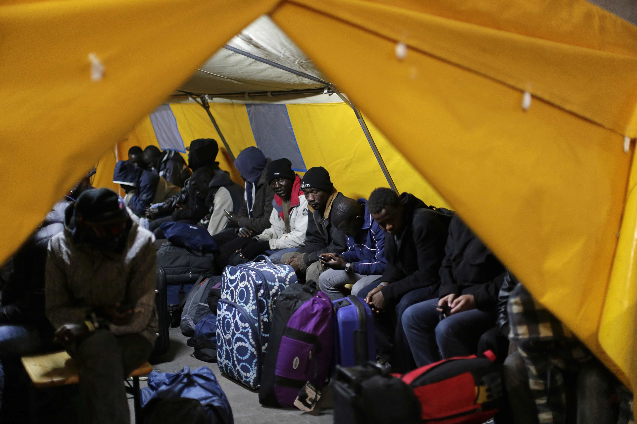 Migrants sit inside a tent as they are registered at a processing center in the makeshift migrant camp known as  the Jungle,  near Calais, northern France, on Oct. 24, 2016.