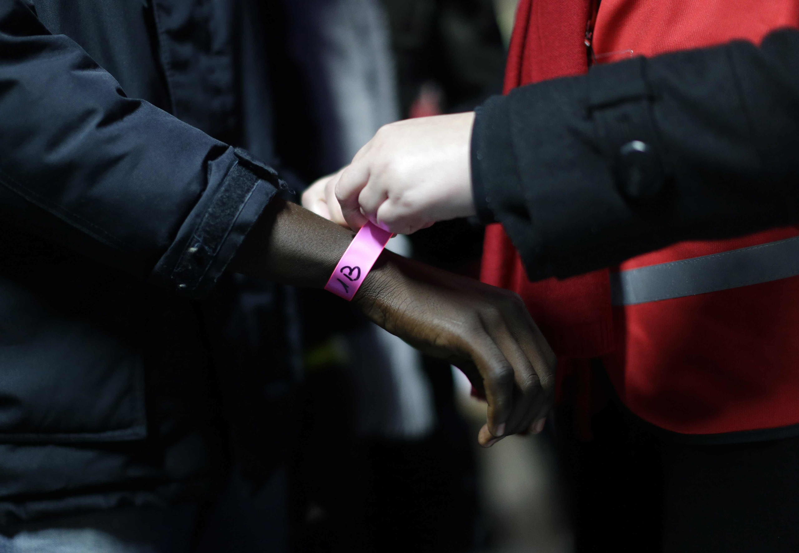 A wristband is attached to a migrant at a processing center in the makeshift migrant camp known as  the Jungle,  near Calais, northern France, on Oct. 24, 2016.