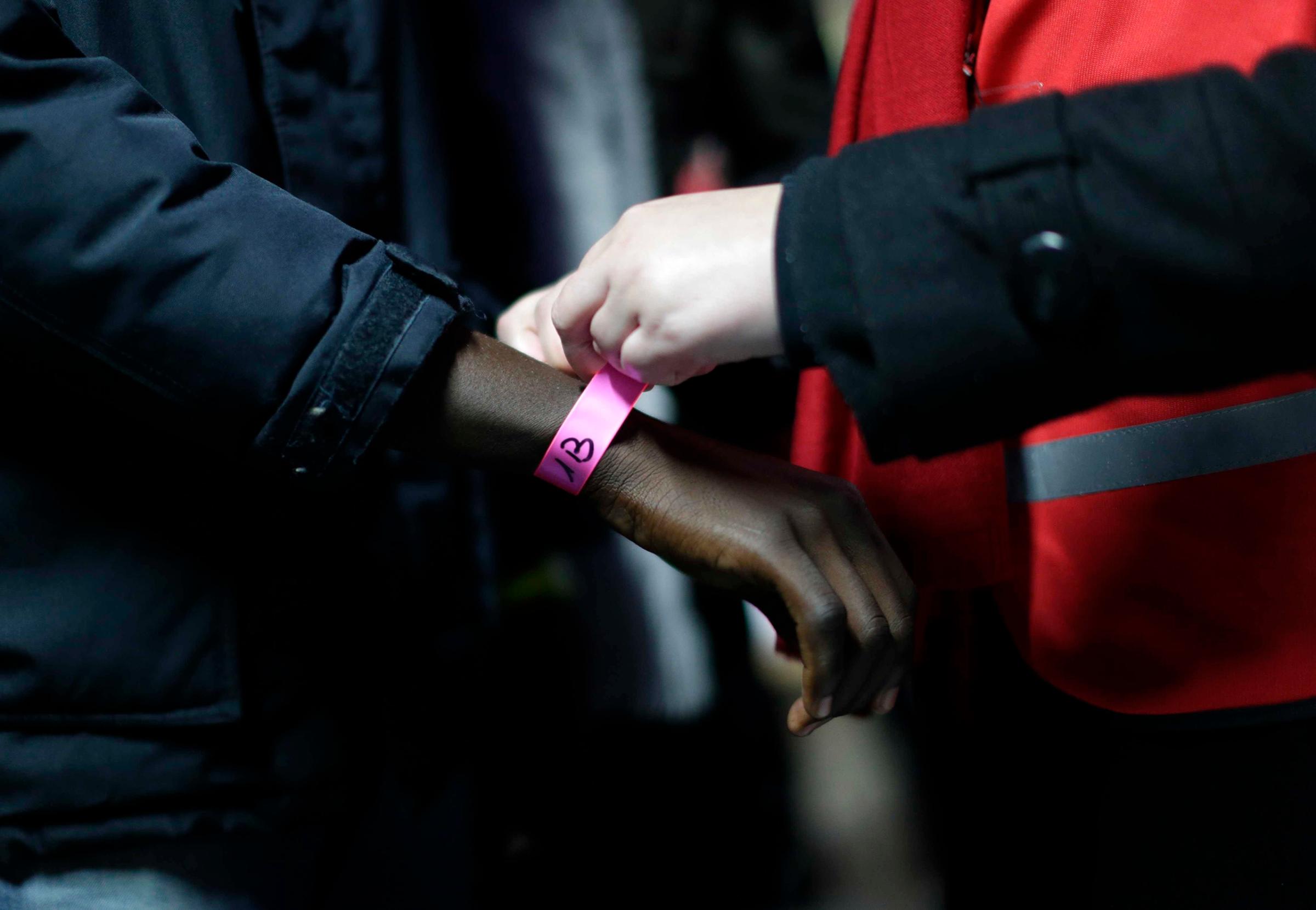 A wristband is attached to a migrant at a processing center in the makeshift migrant camp known as "the Jungle," near Calais, northern France, on Oct. 24, 2016.