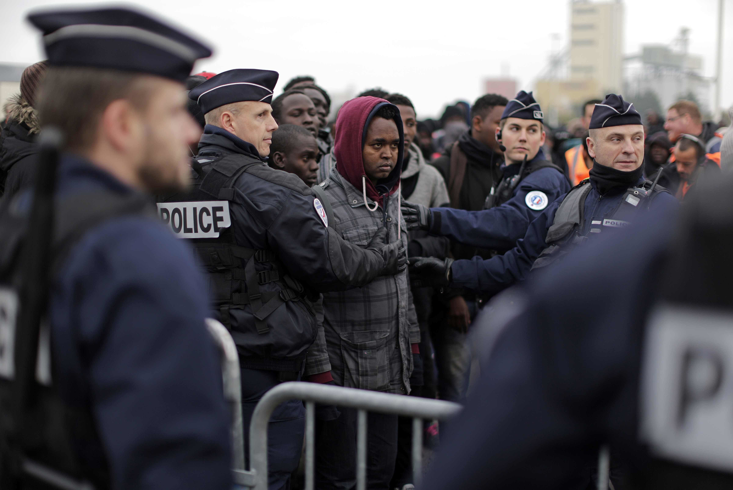 Police officers control a line as migrants line up to register at a processing center in the makeshift migrant camp known as  the Jungle,  near Calais, northern France, on Oct. 24, 2016.