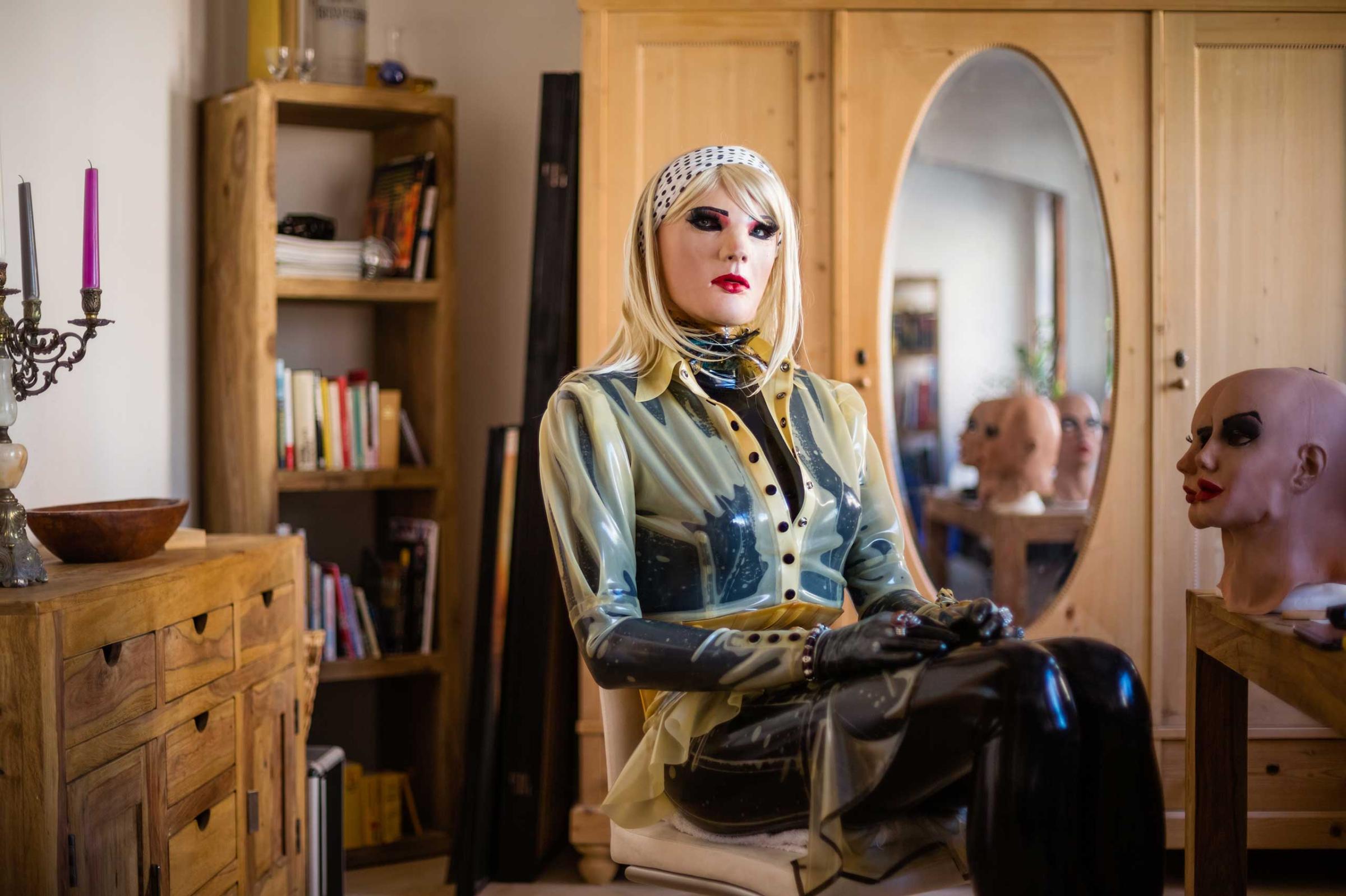 AUGSBURG, GERMANY - AUGUST 05, 2015: Portrait of female masker Christian alias 'Chrissie Seams', double the age of his alter ego, in his living-room, August 05, 2015 in Augsburg, Germany. Female masking presents an outlet for him, as a heterosexual and cisgender male, to live out his female side and latex fetish. On his right stand a variety of masks that he uses for experimenting with airbrushing and other alteration techniques in order to individualise the look of his alter ego. "Since my childhood I have been fascinated by latex, which very soon merged with my aspirations to look as sexy as a woman. I remember the first time I had the wish to slip into a woman’s skin was at the age of 14 when I saw a model wearing sexy lingerie in a Penthouse magazine. I imagined slipping into her skin, like slipping into a surface made from latex.I love the feeling of being encapsulated and the sensitization from head to toe when wearing latex. At the same time I endeavor aesthetics. Visually, I only like latex on women, hence I don’t gain anything from my fetish if not dressed as a woman myself. Many times I wondered if there was a Chrissie if it wasn’t for my passion for latex."- Female masker Christian alias Chrissie Seams, heterosexual man, double the age of his alter ego