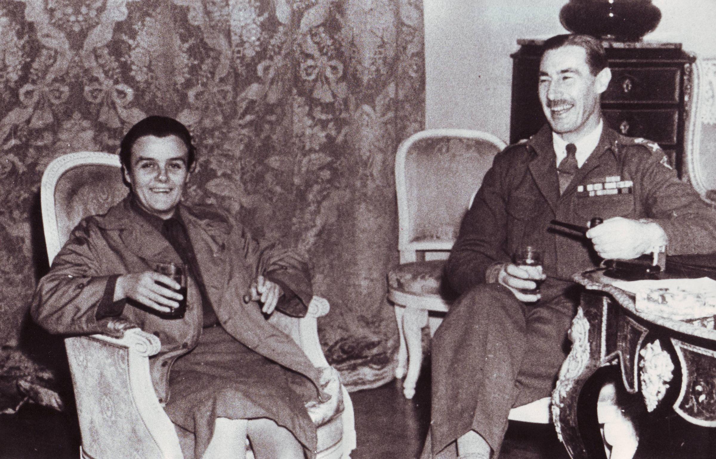Clare Hollingworth with a military figure lounging in arm chair, likely towards the end of World War II.
