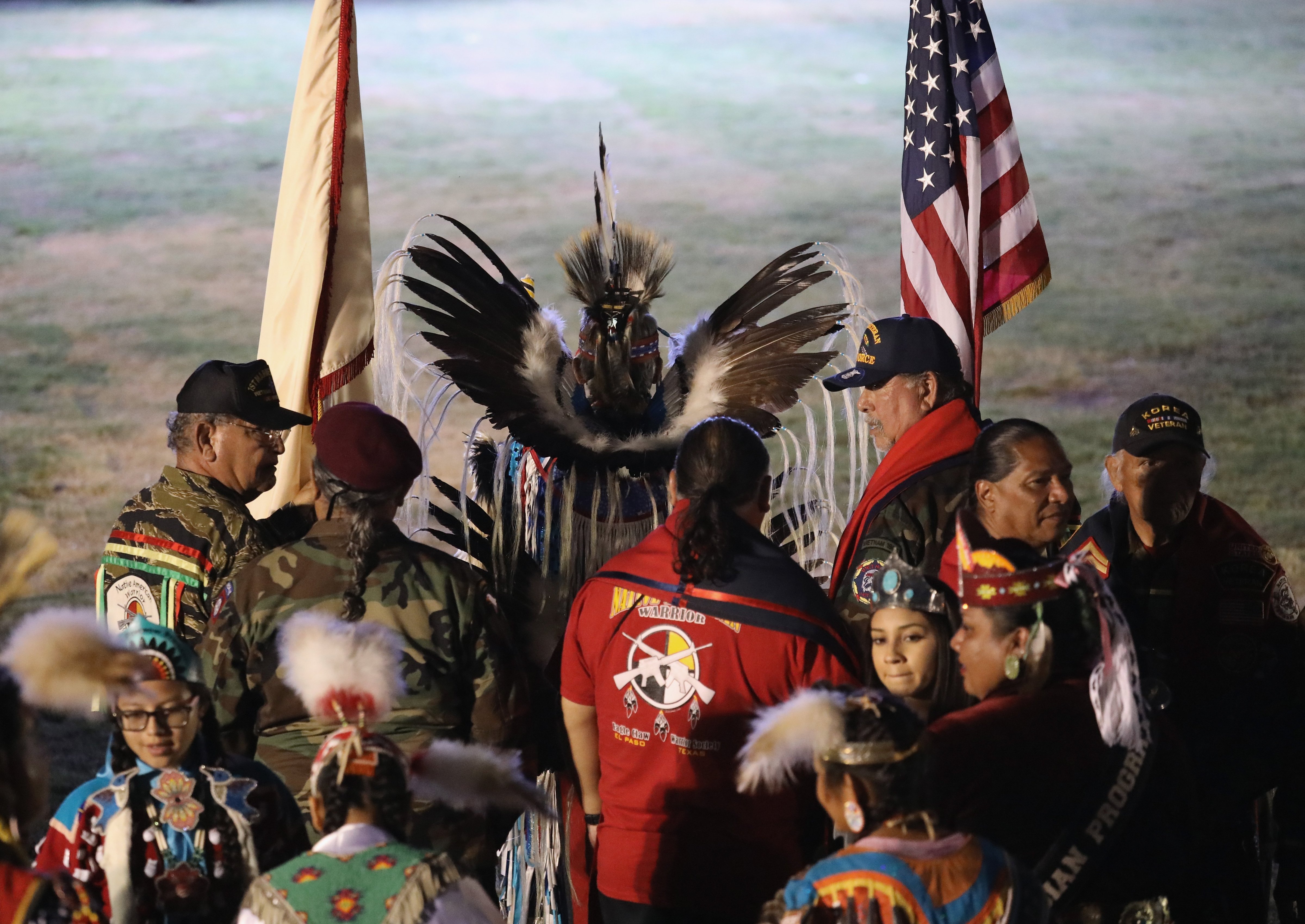 Native American veterans carry U.S. and tribal flags before entering the 