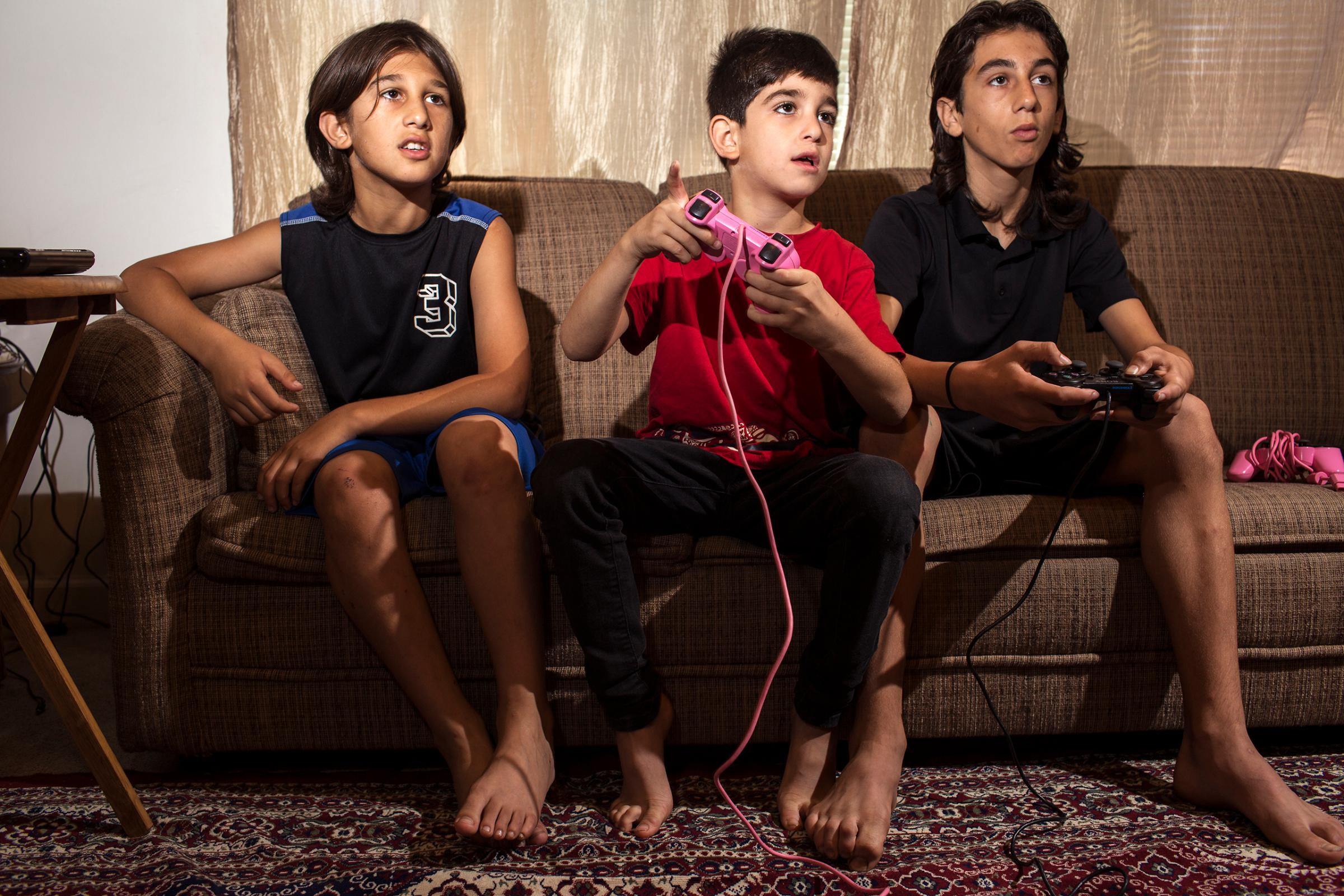Haidar, Mutaz and Nazeer Tameem play video games at their apartment in Des Moines, Iowa.