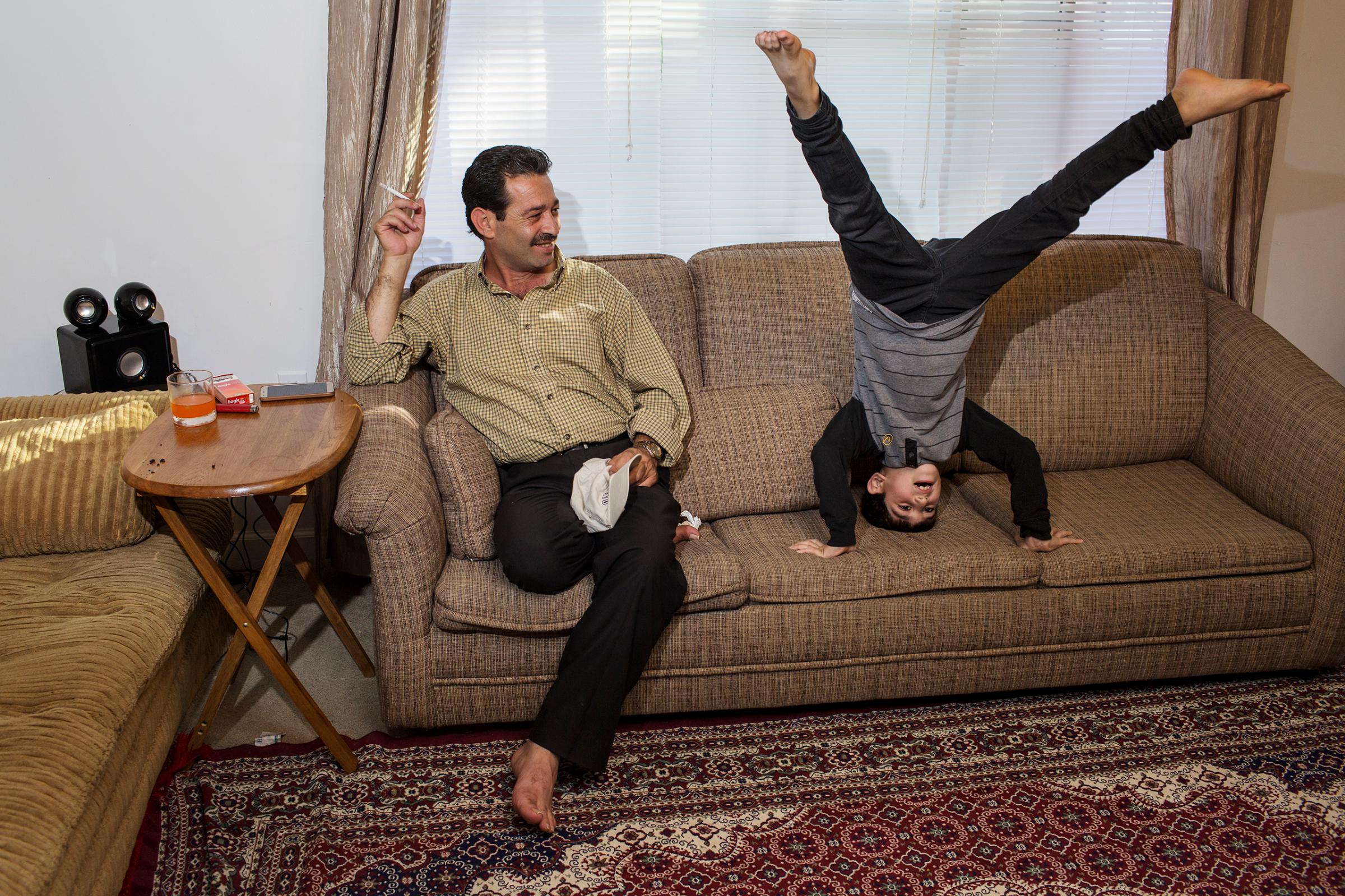 Mutaz Tameem, 6, plays inside the family's apartment in Des Moines, Iowa, while his father, Abdul Fattah, looks on.