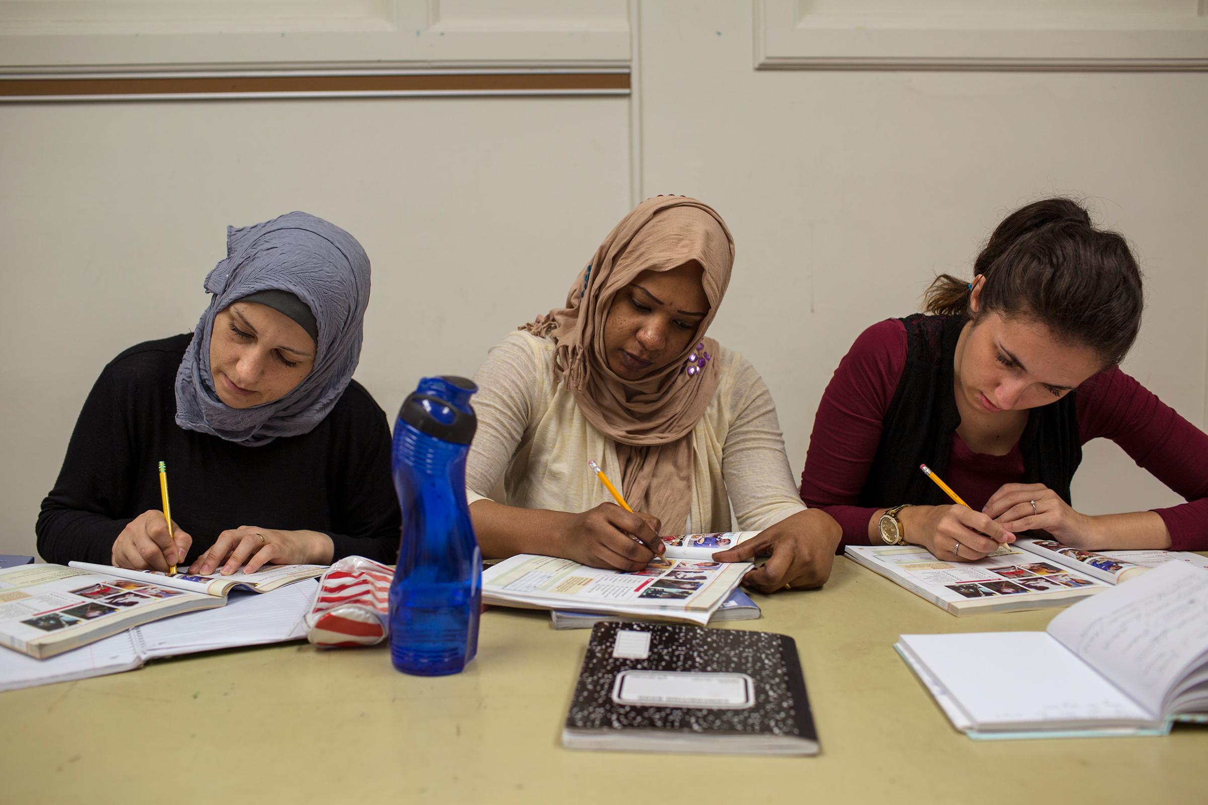 Ghazwa, Mrwah Shanpia and Arnela Omerovic write during their ESL class at the Des Moines Area Community College.