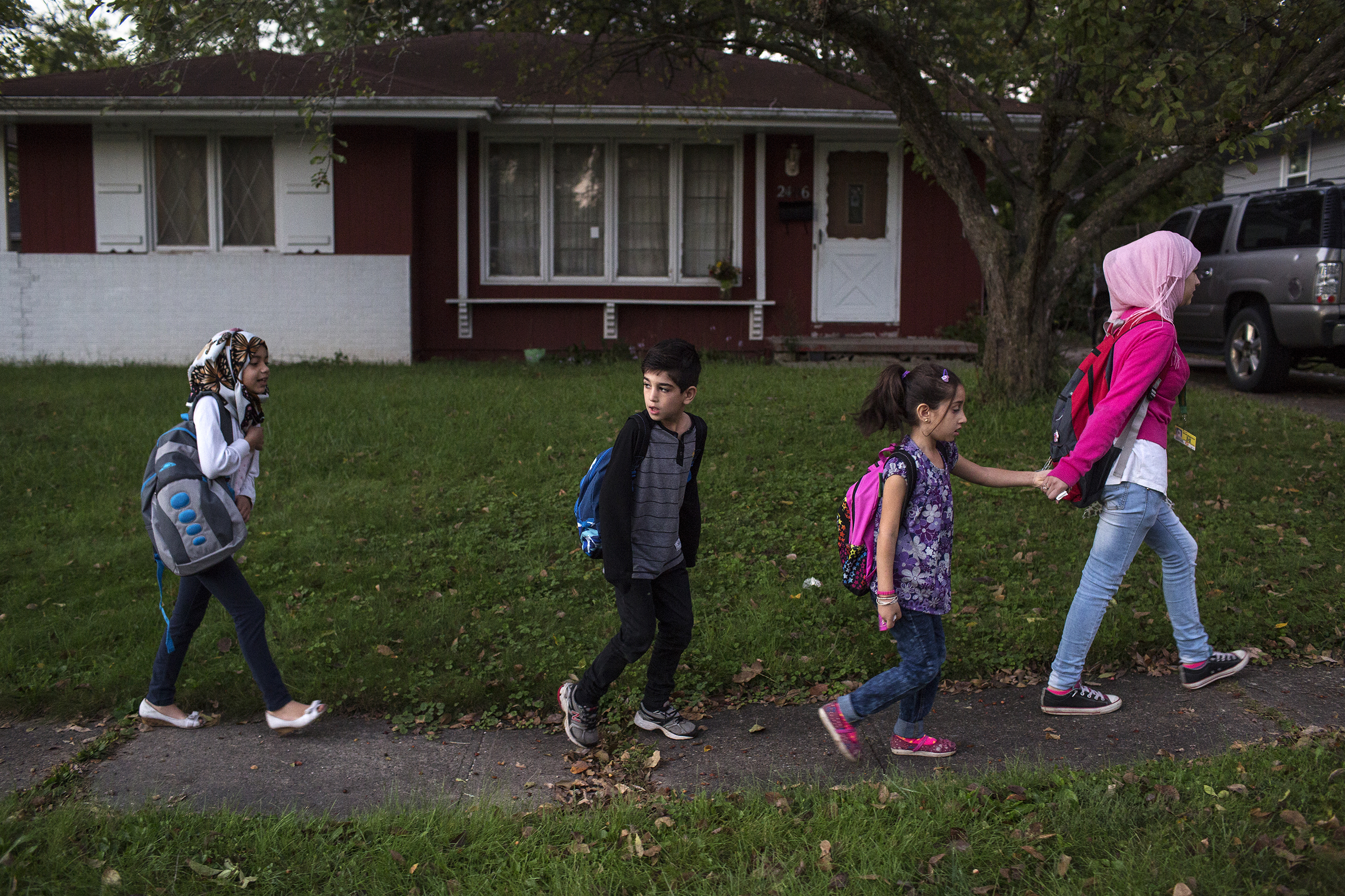 Sedra walks her brother Mutaz, sister Hala (with pink backpack) and a friend to their school-bus stop in the family’s neighborhood in Des Moines.
