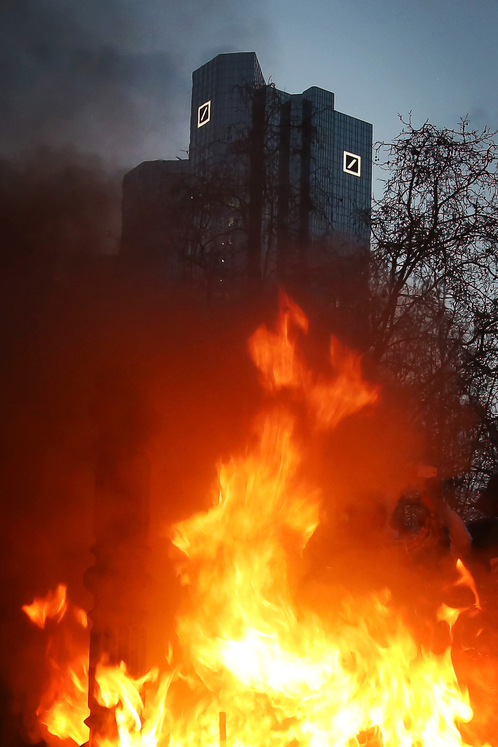 Protesters set fire to a pile of fake bills in front of the towers of the Deutsche Bank, while gathering for the closing rally on the Opernplatz (Opera Square) in Frankfurt, Germany, 18 March 2015. The new headquarters of the European Central Bank (ECB) in Frankfurt opened today amid protests. Photo by: Fredrik von Erichsen/picture-alliance/dpa/AP Images (Fredrik von Erichsen)