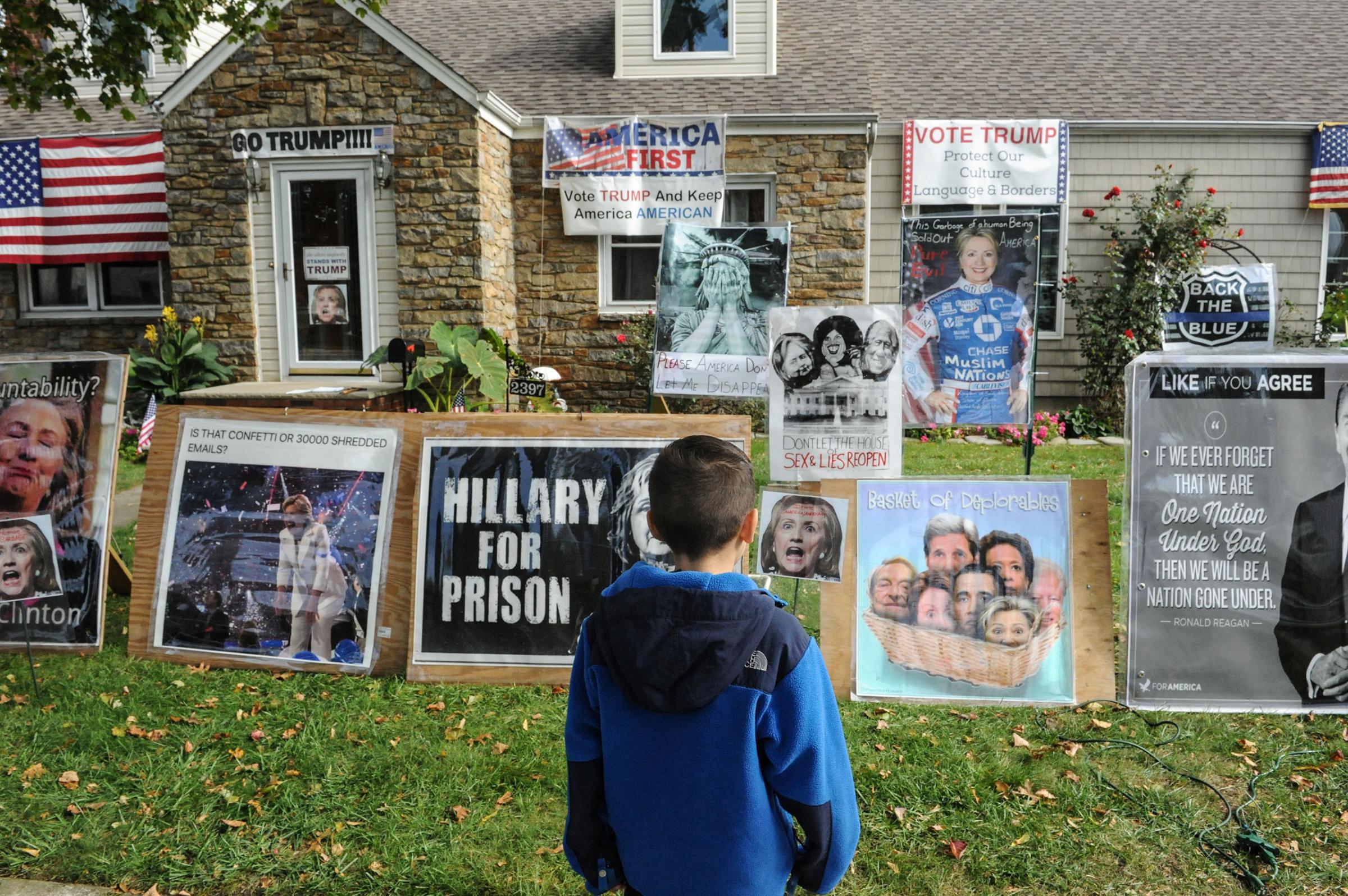Dominick Vaglica, age 7, looks at a home displaying signs supporting Donald Trump and criticizing Hillary Clinton in Bellmore, NY, on Oct. 29, 2016.
