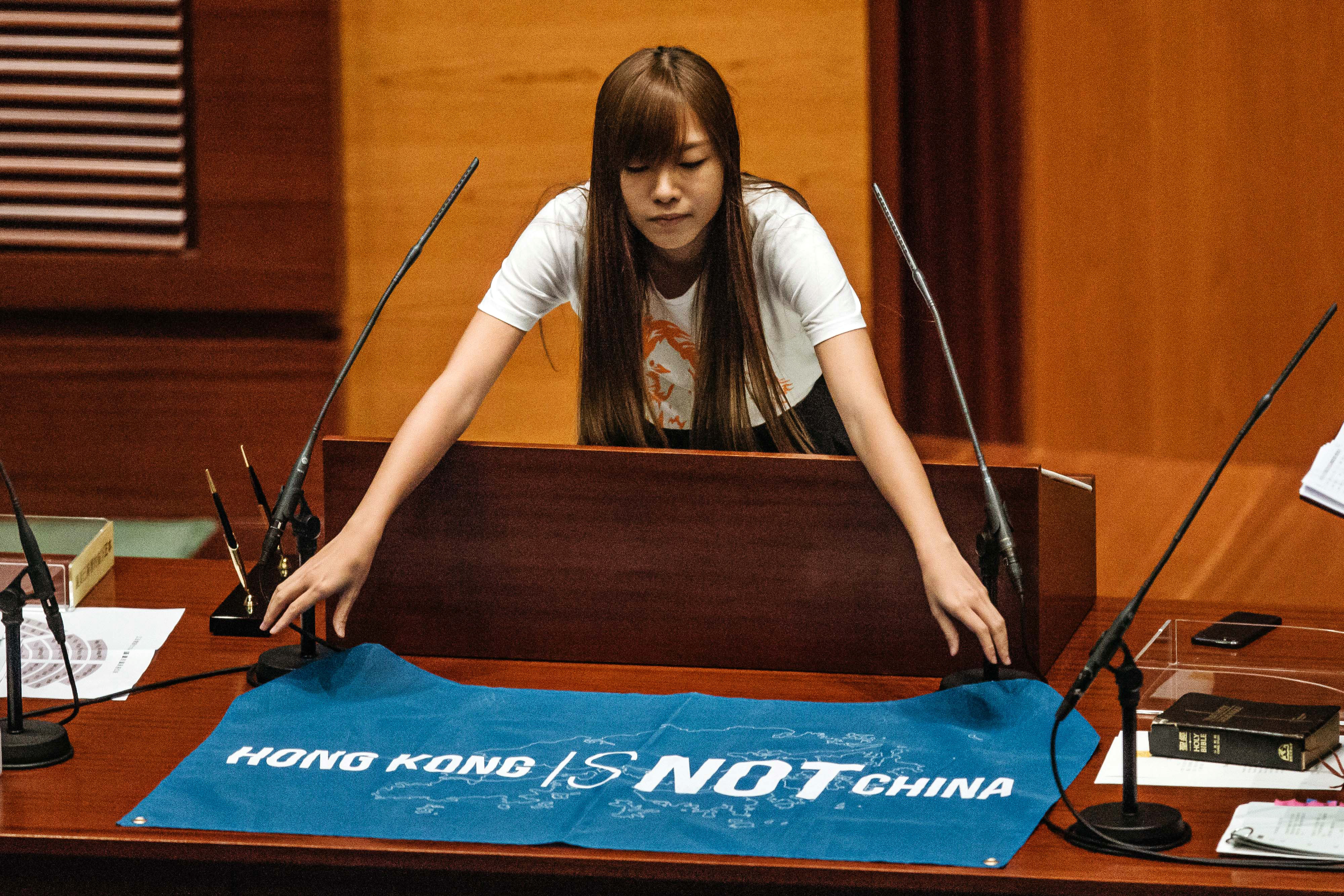 Yau Wai-ching, an incoming lawmaker and member of Youngspiration, unfurls a banner that reads "Hong Kong Is Not China" during an oath-taking ceremony in the chamber of the Legislative Council in Hong Kong on Oct. 12, 2016 (Anthony Kwan—Bloomberg/Getty Images)