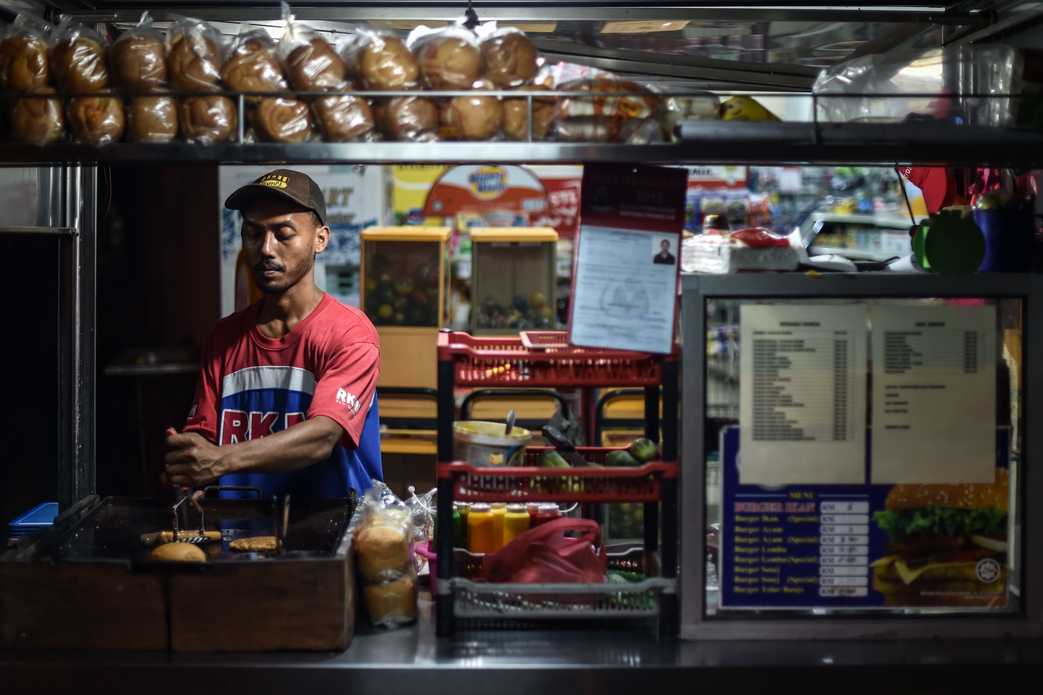 An employee cooks burgers and hotdogs at a roadside stall in Karak, outside Kuala Lumpur, on Oct. 18, 2016 (Mohd Rasfan—AFP/Getty Images)