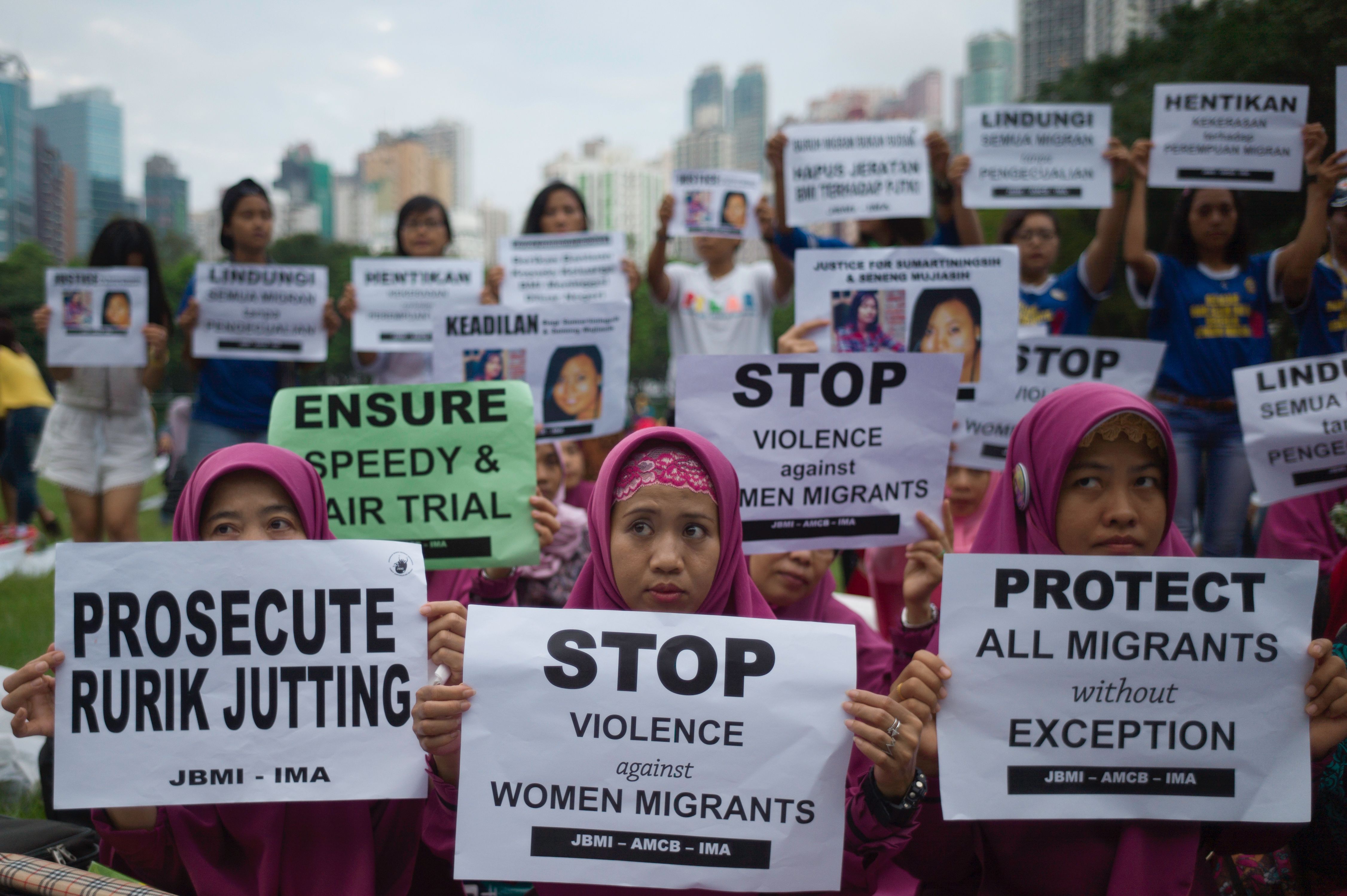 Indonesian migrant workers hold up placards during a vigil for slain colleagues Seneng Mujiasih and Sumarti Ningsih on the eve of the murder trial for British banker Rurik Jutting, in Hong Kong's Victoria Park on Oct. 23, 2016 (Tengku Bahar—AFP/Getty Images)