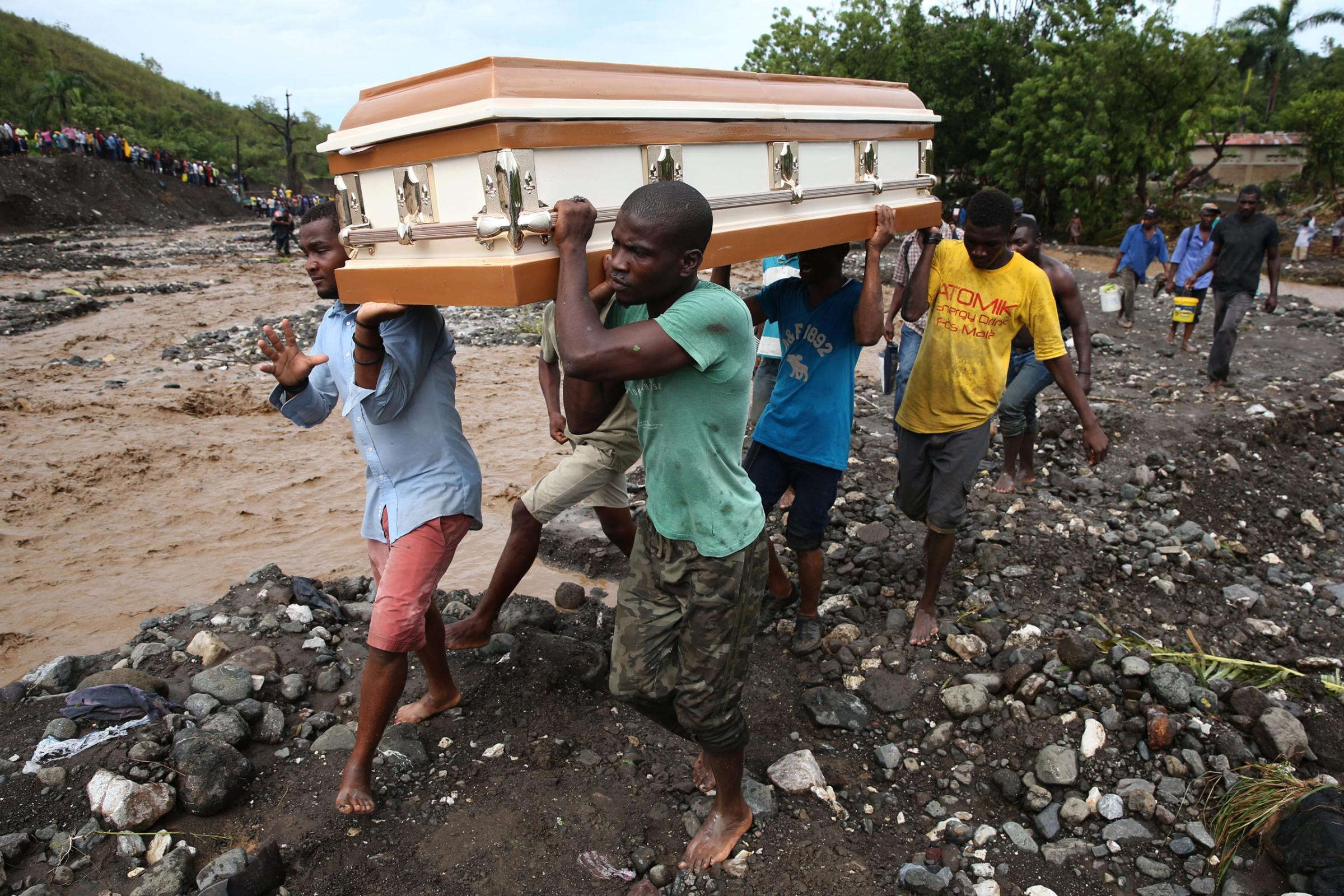 epaselect epa05572082 A group of people carry a coffin and try to cross the river La Digue, after the colapse of the only bridge that connects to the south after the passing of hurricane Matthew in the country, in Petit Goave, Haiti, 05 October 2016. The hurricane Matthew left at least nine dead on last 04 October. The impact of Hurricane Matthew in Haiti, which left at least nine dead and thousands displaced, mainly in southwestern communities, forced the electoral authorities to postpone Sunday's election. EPA/Orlando Barria