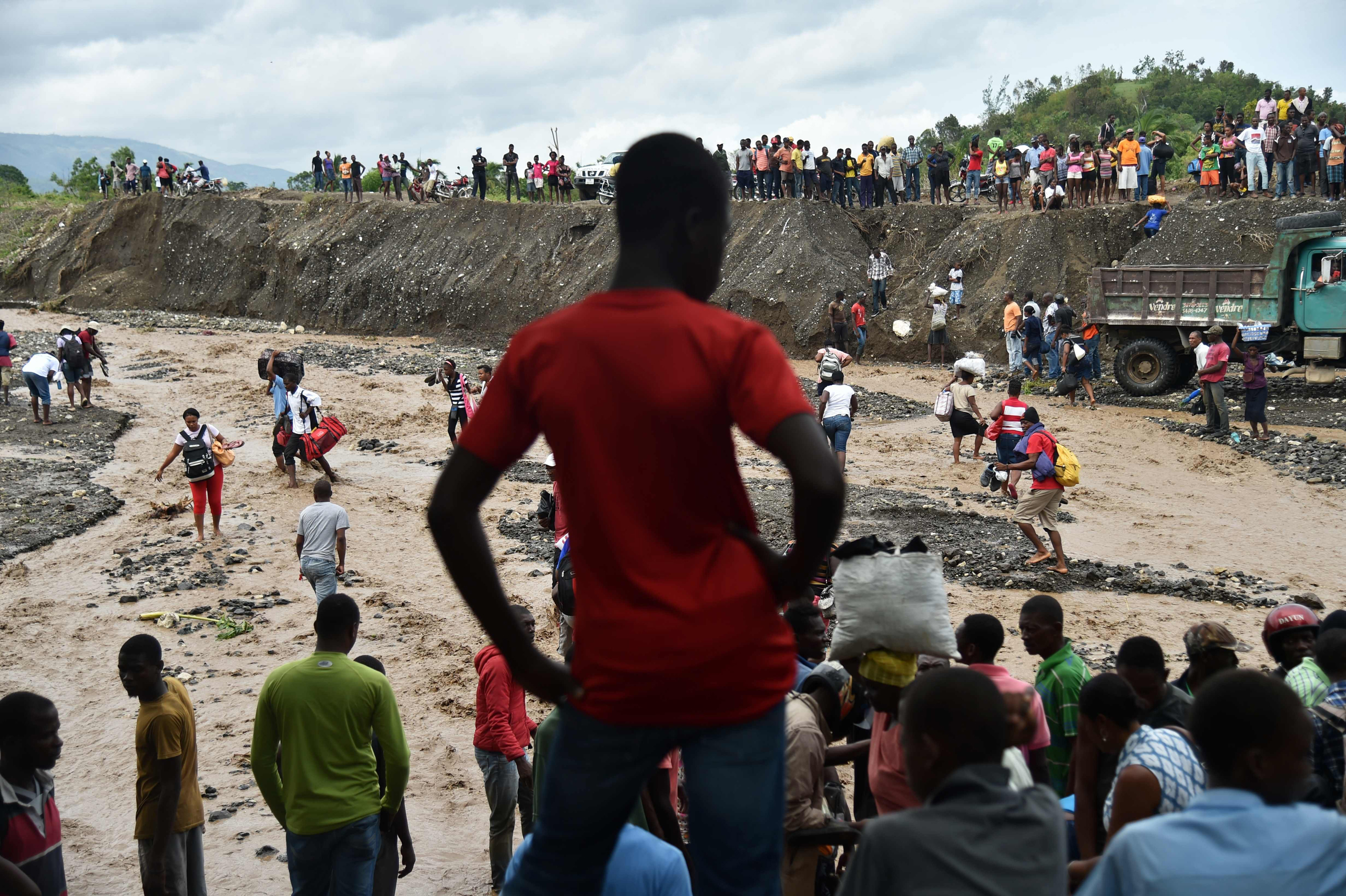 Haitian people cross the river La Digue, where the bridge collapsed during the rains from Hurricane Matthew, in Petit Goave, Haiti, on Oct. 6, 2016.