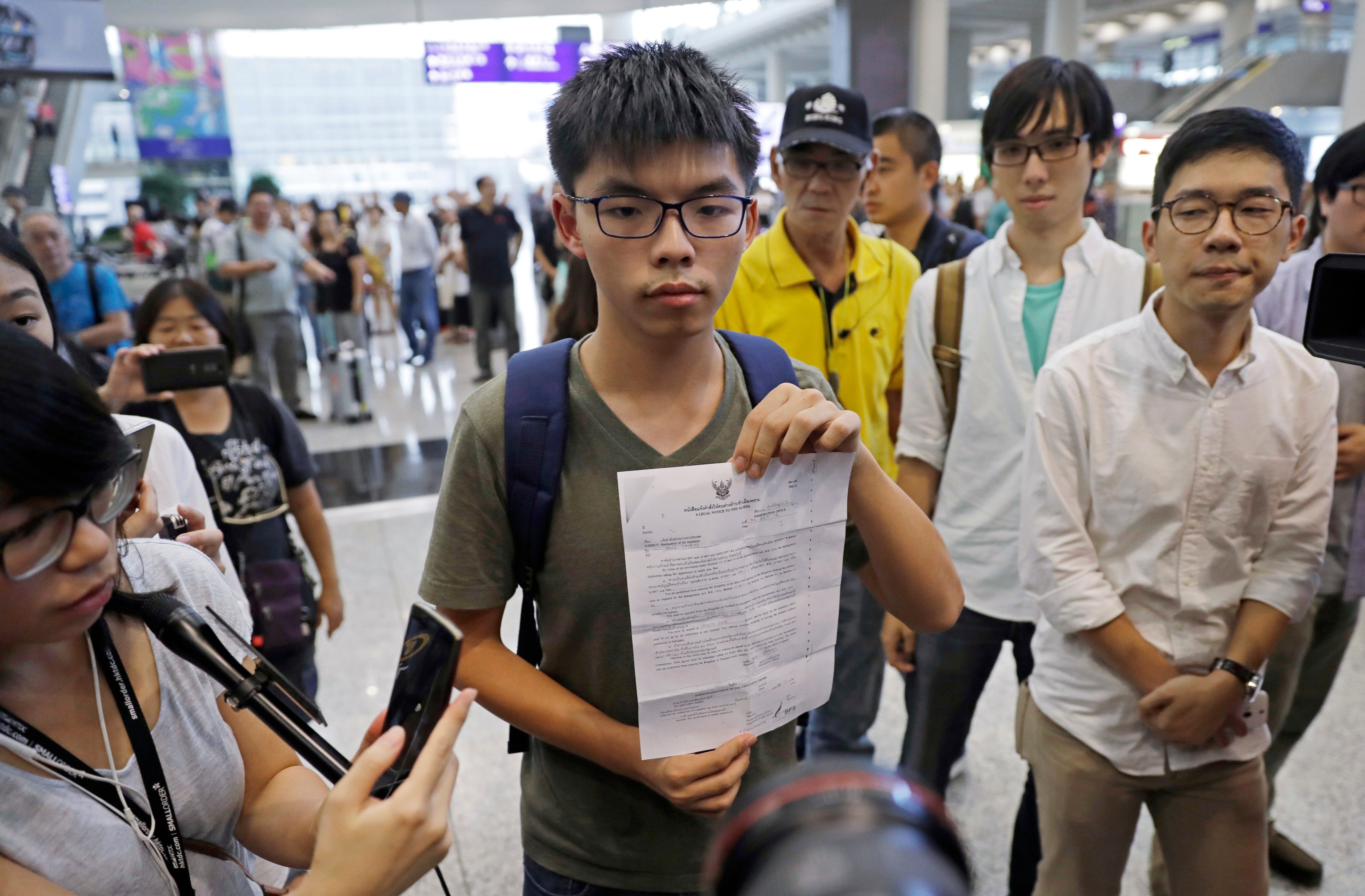 Hong Kong pro-democracy activist Joshua Wong, center, shows a letter from Thailand's immigration office after arriving at Hong Kong airport from Bangkok on Oct. 5, 2016. Thailand stopped the 19-year-old activist from entering the country and sent him back to Hong Kong, officials said, in a move supporters suspected was triggered by pressure from Beijing (Kin Cheung—AP)