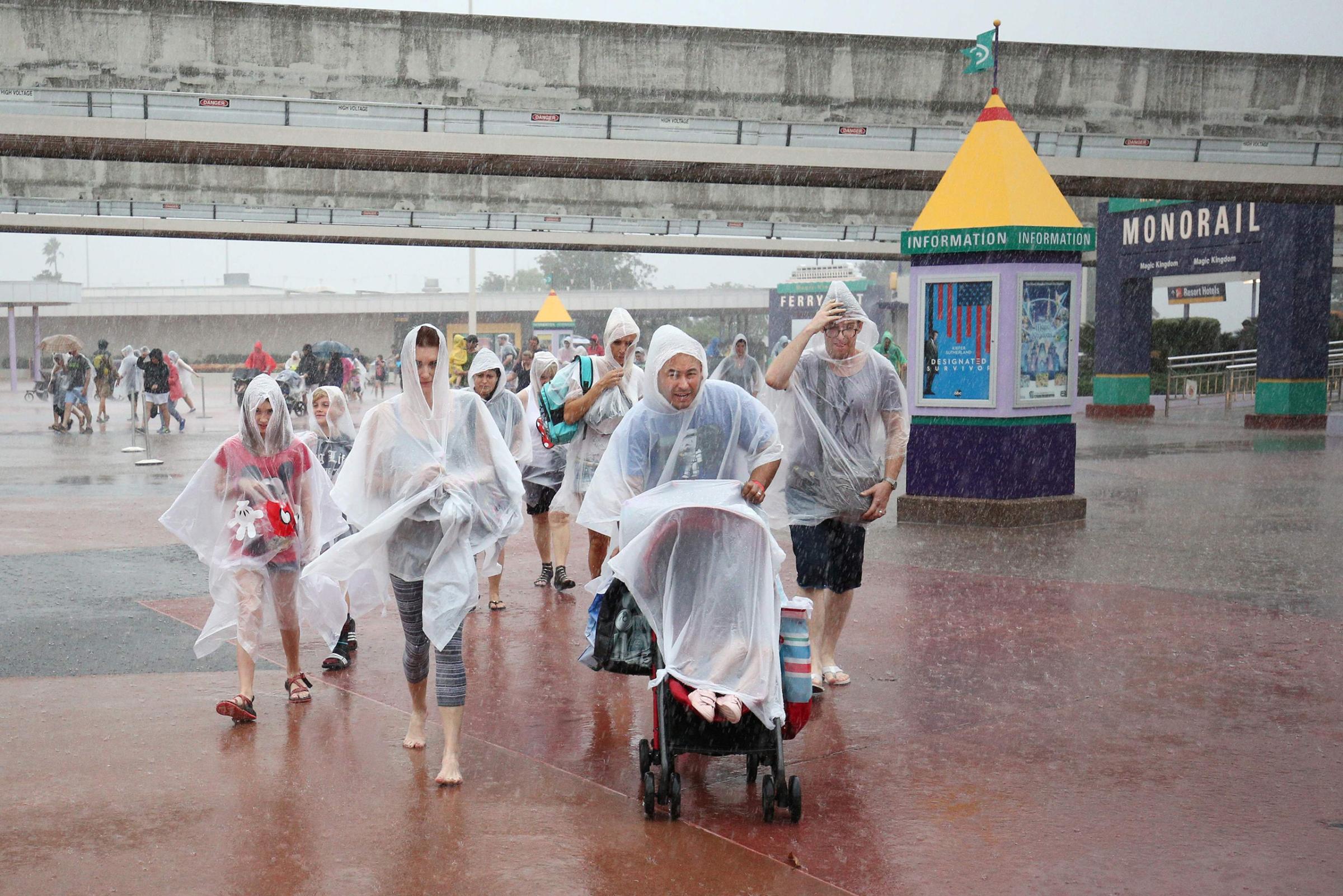 People leave Disney's Magic Kingdom theme park, in heavy rain, after it closed in Orlando, Fla., in preparation for the landfall of Hurricane Matthew, on Oct. 6, 2016.
