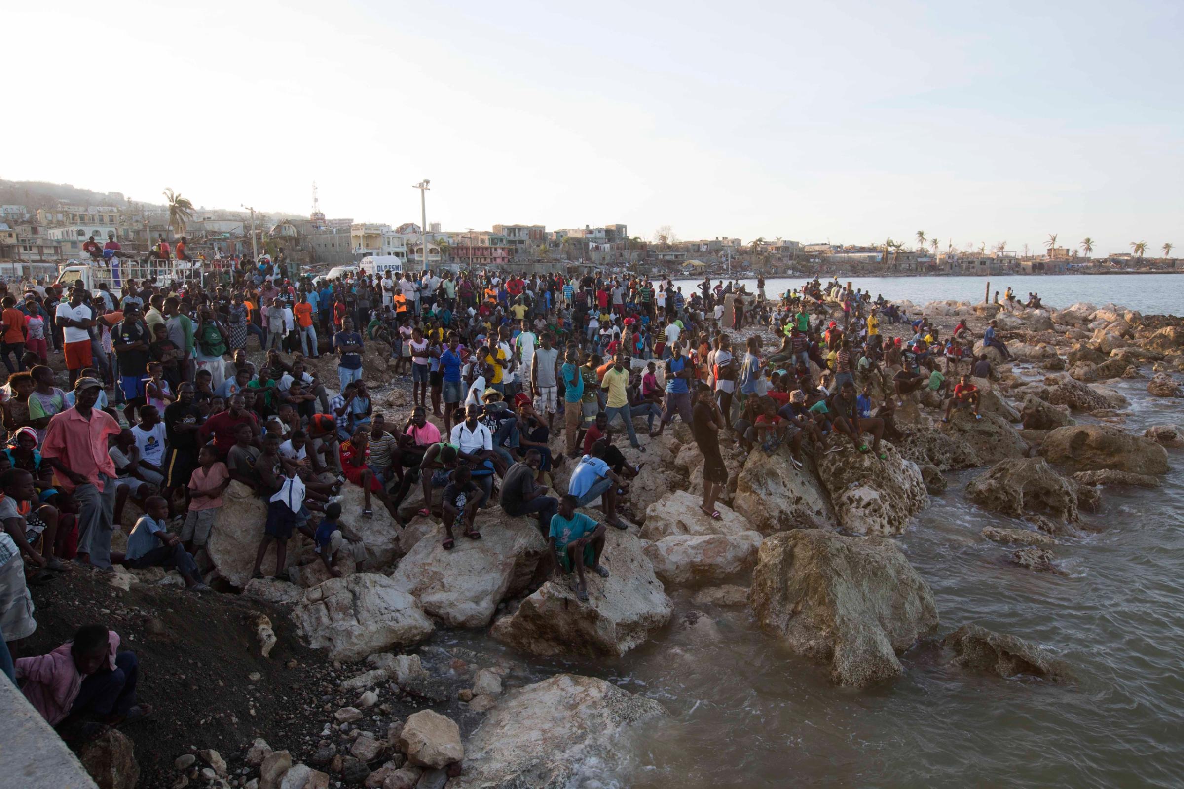 Residents wait on the shore as a boat with water and food from the "Mission of Hope" charity arrives after Hurricane Matthew swept through Jeremie, Haiti, Saturday Oct. 8, 2016. Jeremie appears to be the epicenter of the country's growing humanitarian crisis in the wake of the storm. (AP Photo/Dieu Nalio Chery)