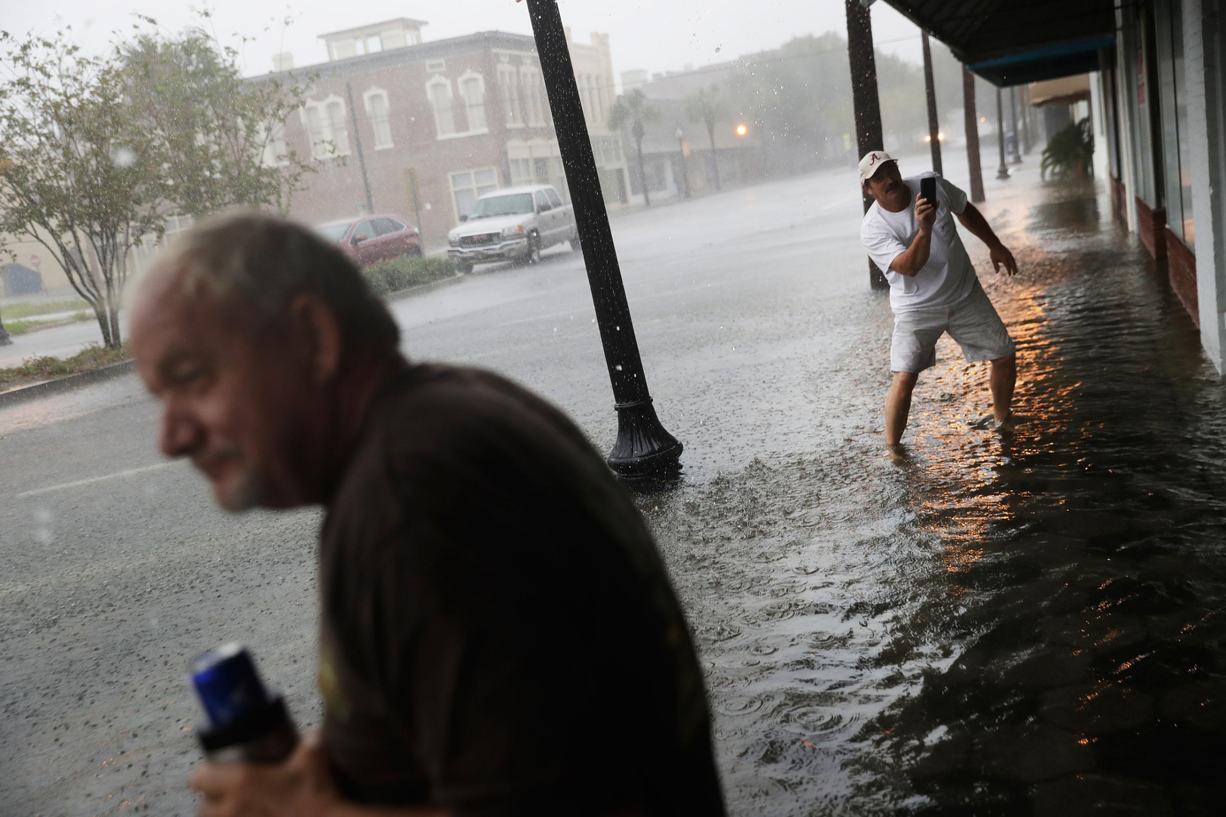 Keith Paseur, right, and Pat Barlow survey a flooded street from Hurricane Matthew as they check on a neighbor riding out the storm in their store in downtown Brunswick, Ga., Friday, Oct. 7, 2016. (AP Photo/David Goldman)