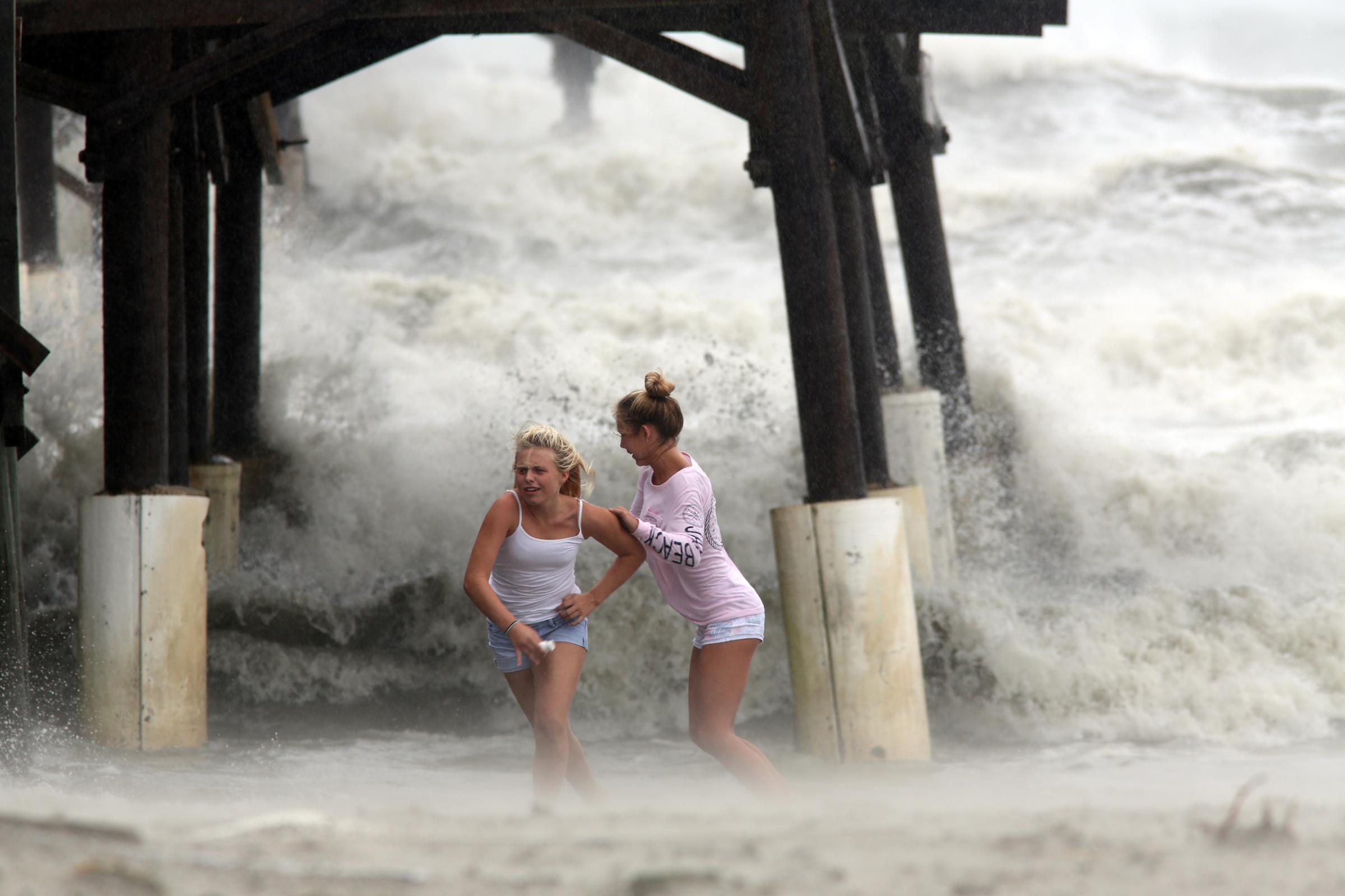 Kaleigh Black, 14, left, and Amber Olsen, 12, run for cover as a squall with rain and wind from the remnants of Hurricane Matthew pelt them as they explore the Cocoa Beach Pier on Friday, Oct. 7, 2016, in Cocoa Beach, Fla. (Douglas R. Clifford/Tampa Bay Times via AP)