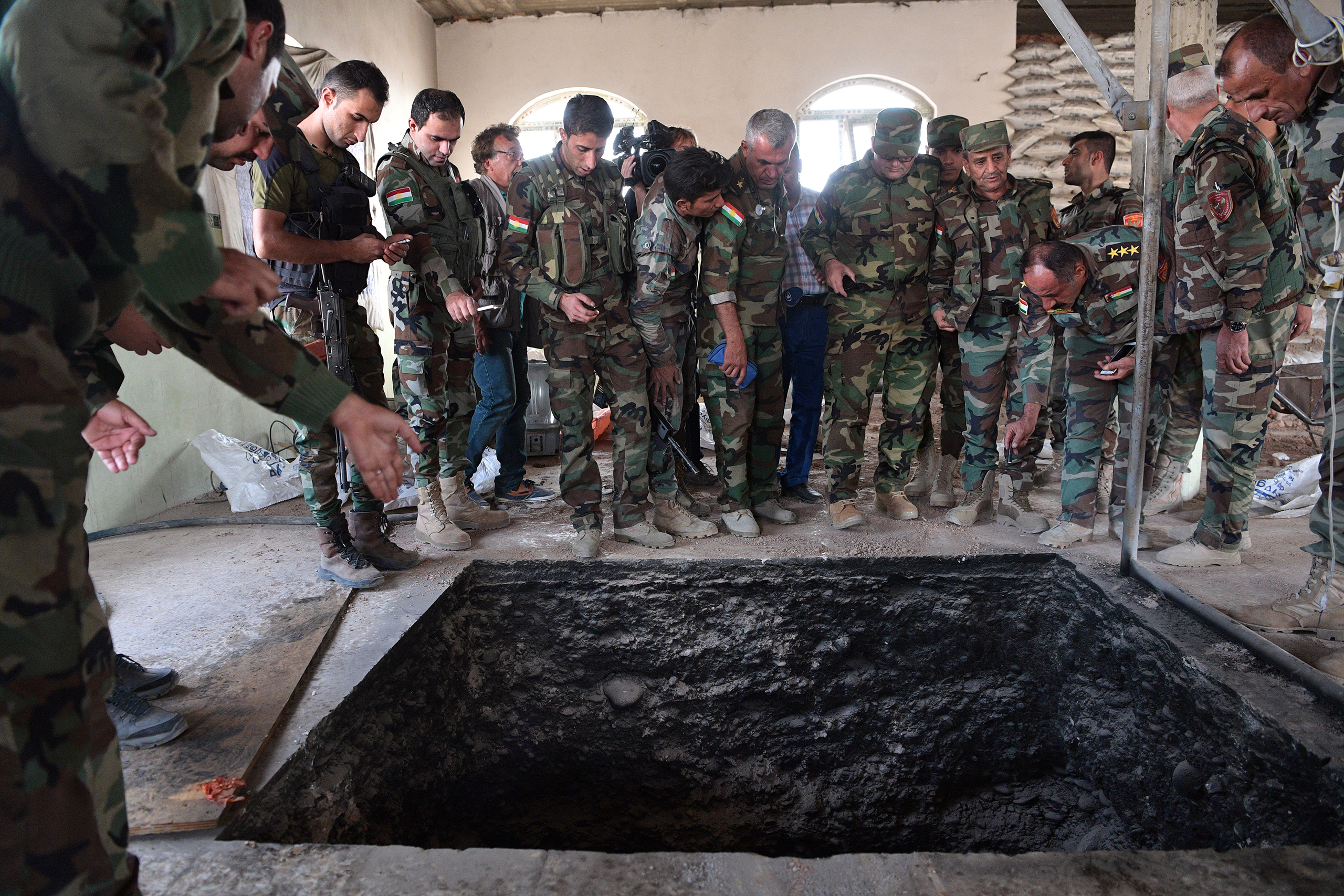 Peshmerga soldiers stand around a tunnel dug by ISIS in a house in Bartella, Iraq, recently recaptured by the Kurds during the battle to retake Mosul on Oct. 18, 2016. (Carl Court—Getty Images)