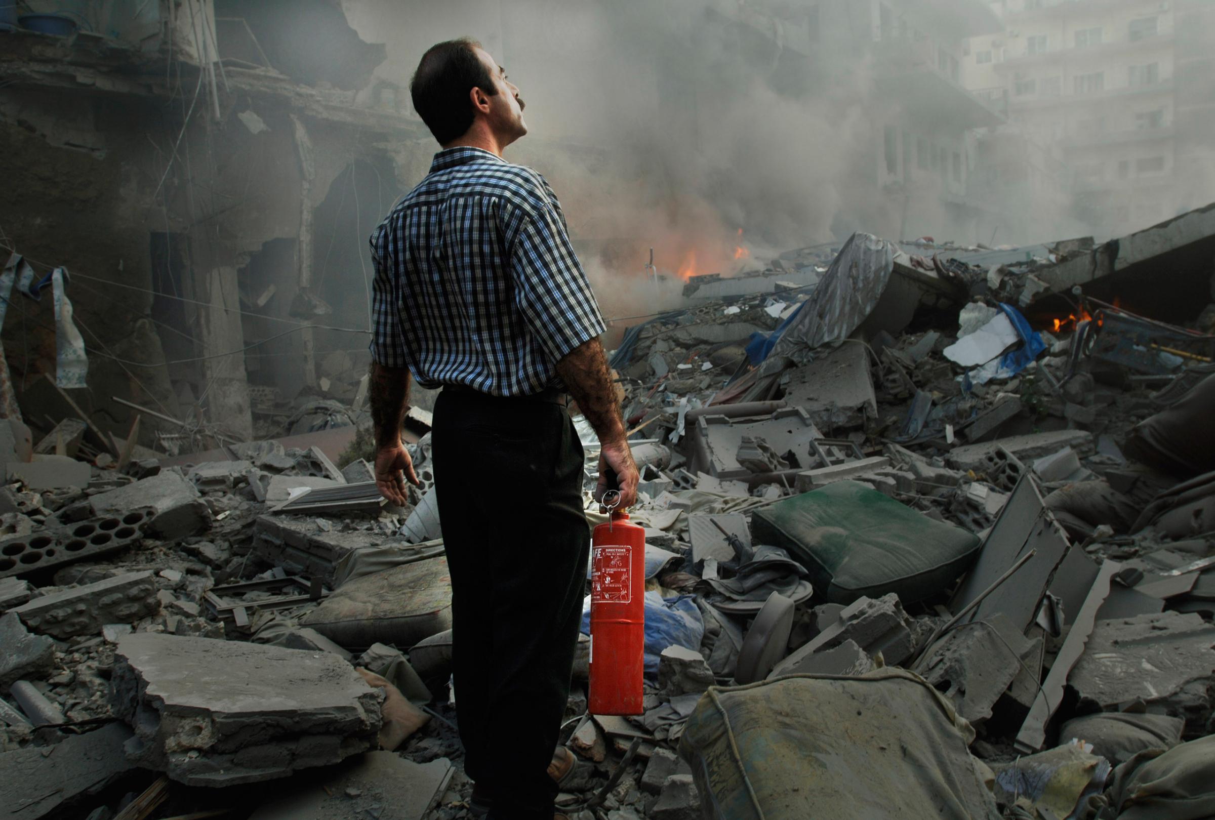 Jeroen Oerlemans, A man looks in despair at the rubble of a six storey apartment building just after it was bombed, realising his small fire extinguisher is not going to be of any use. The building, which was attacked by the Israeli air force, was in the middle of a densely populated area in the city of Tyre.
