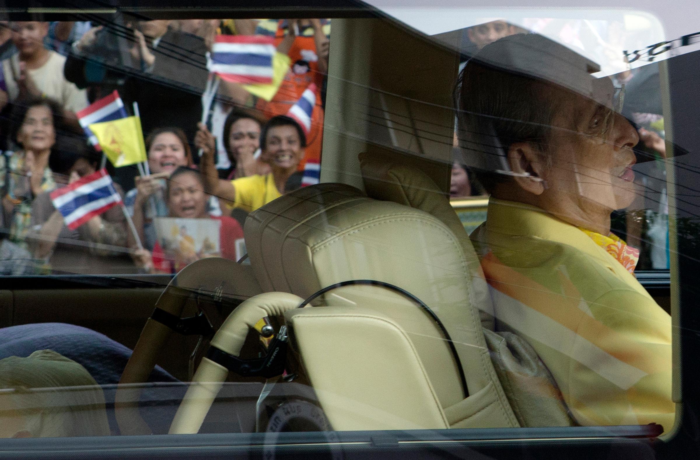Well-wishers wave flags and pray as King Bhumibol Adulyadej leaves Siriraj hospital in Bangkok on Sept. 15, 2014.