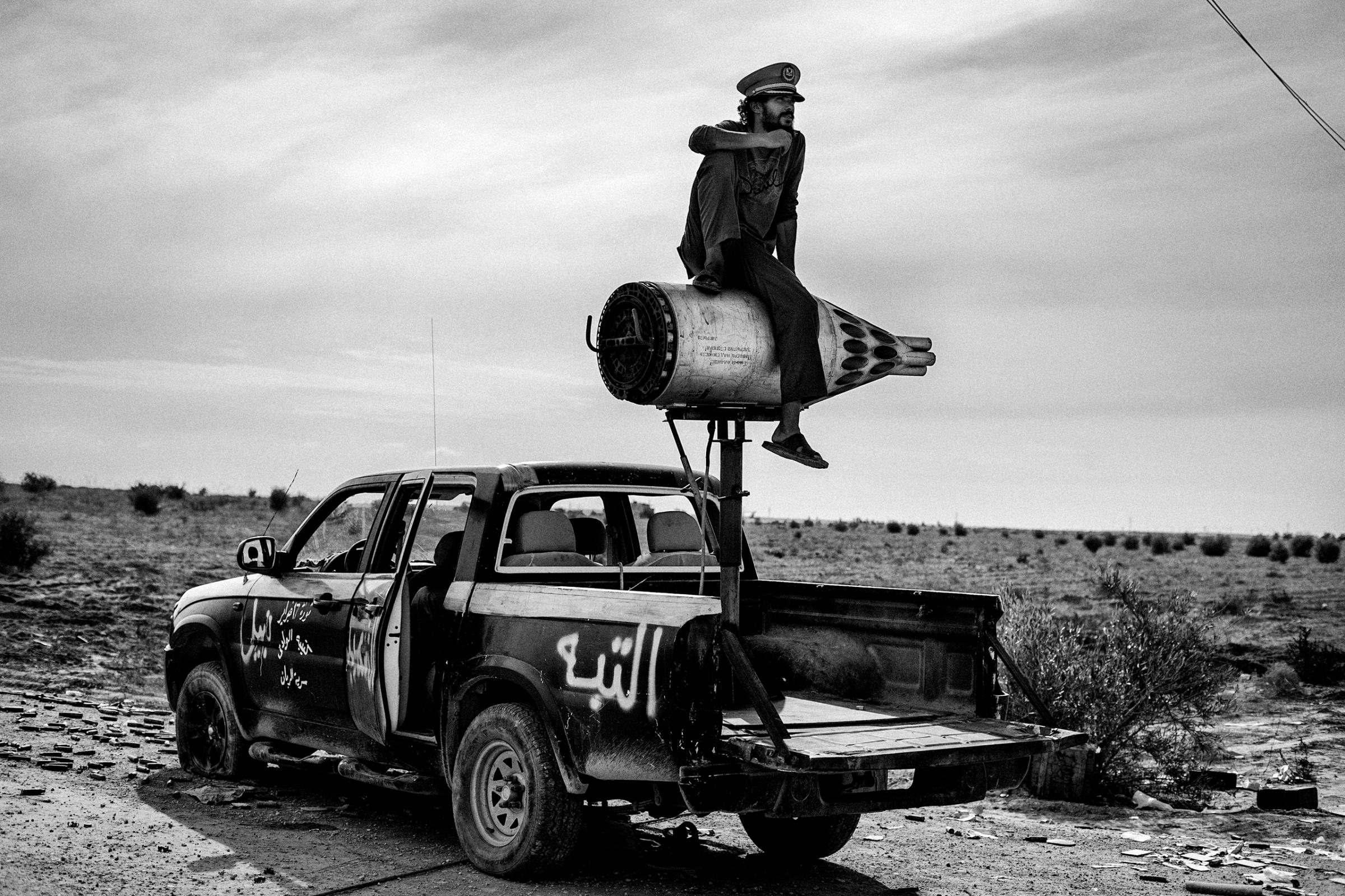 A revolutionary soldier sits on a rocket mounted on a pickup in the desert near Sirte on Oct. 6, 2011.