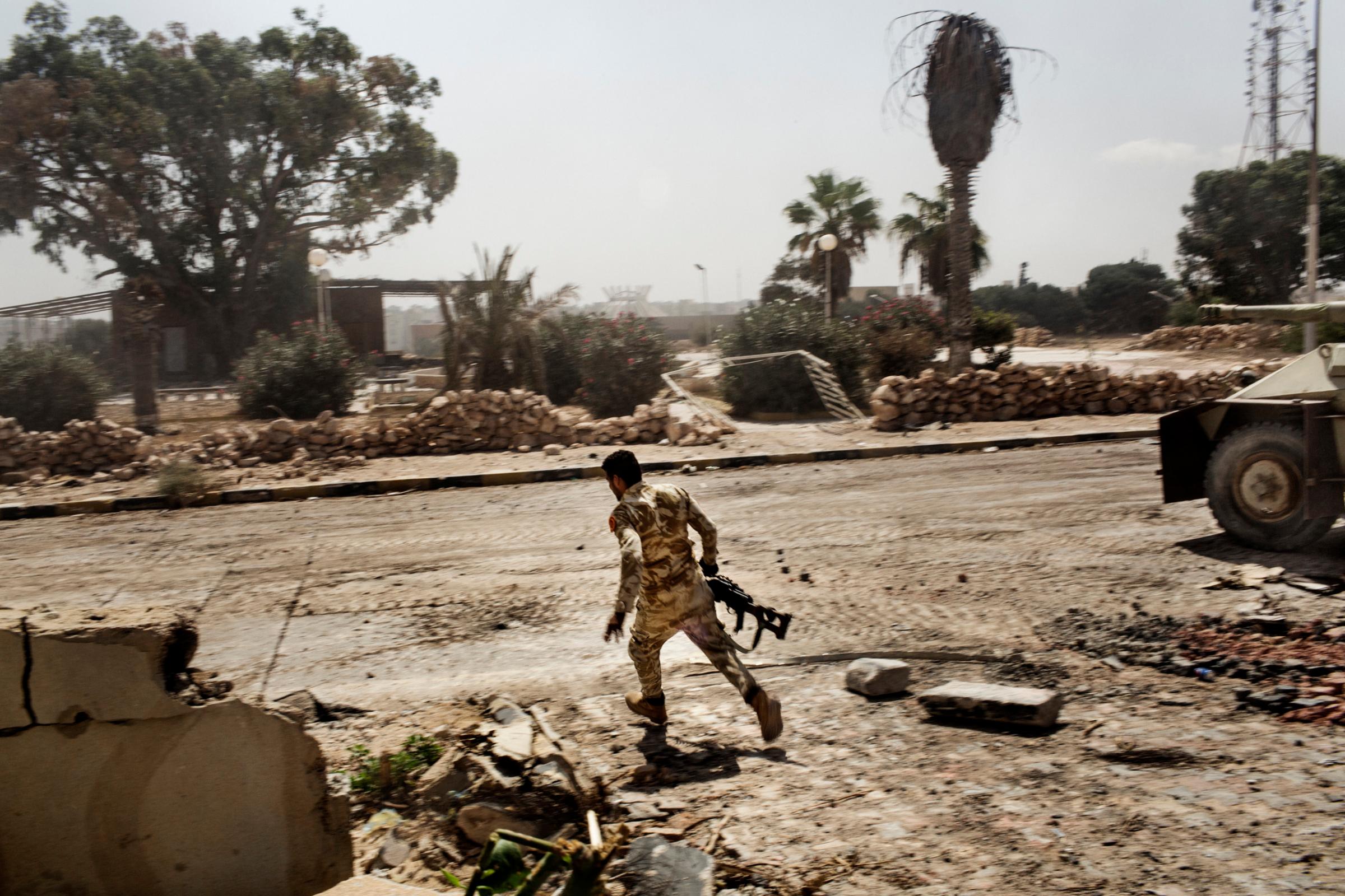 A Libyan fighter affiliated with forces of the Tripoli government runs for cover while fighting against Islamic State positions in Sirte, Libya, Sept. 22, 2016.