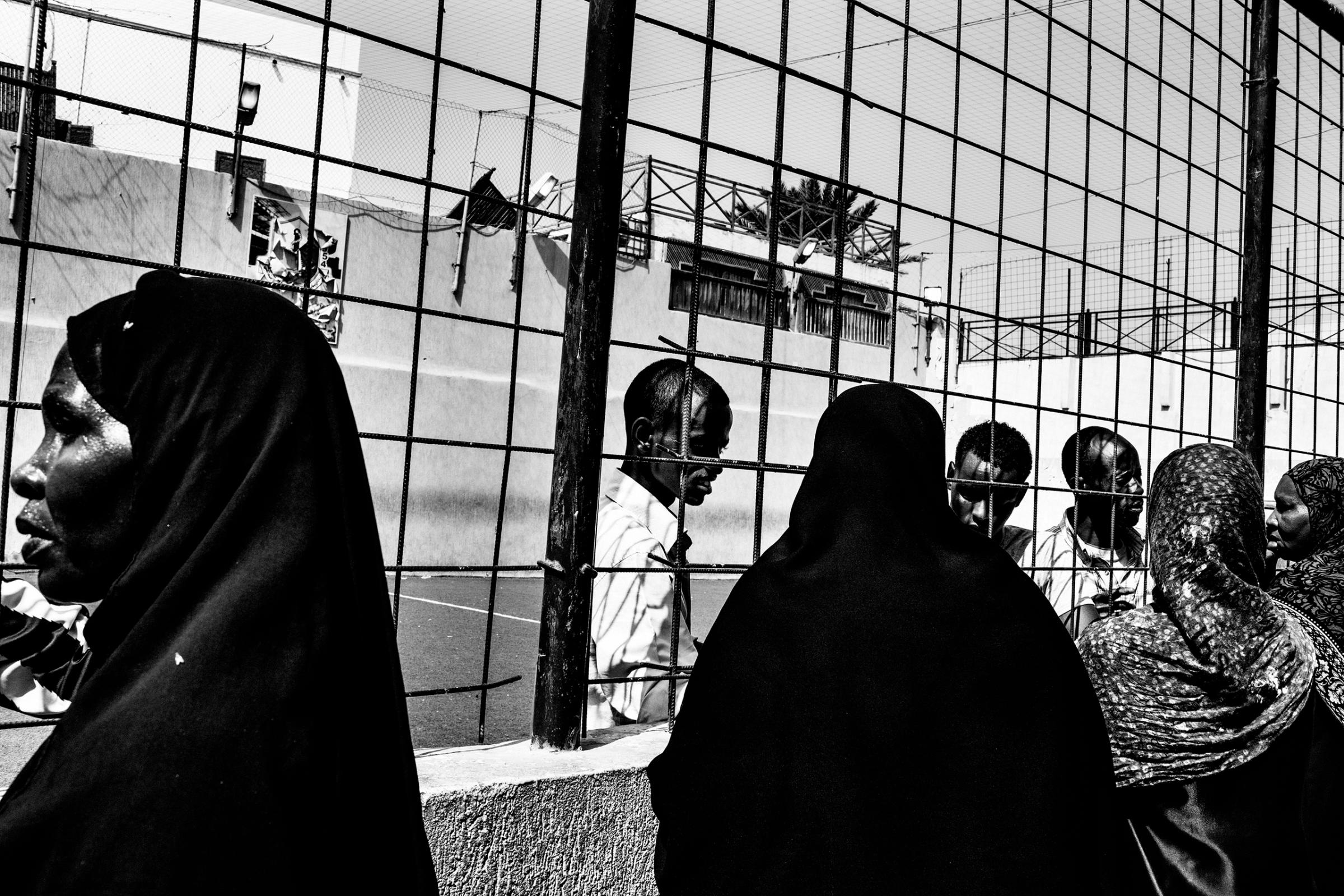 Women talk with thier housbands, suspected to be Gaddafi's mercenaries, imprisoned in a football field converted into a prison, Tripoli on September 2, 2011.