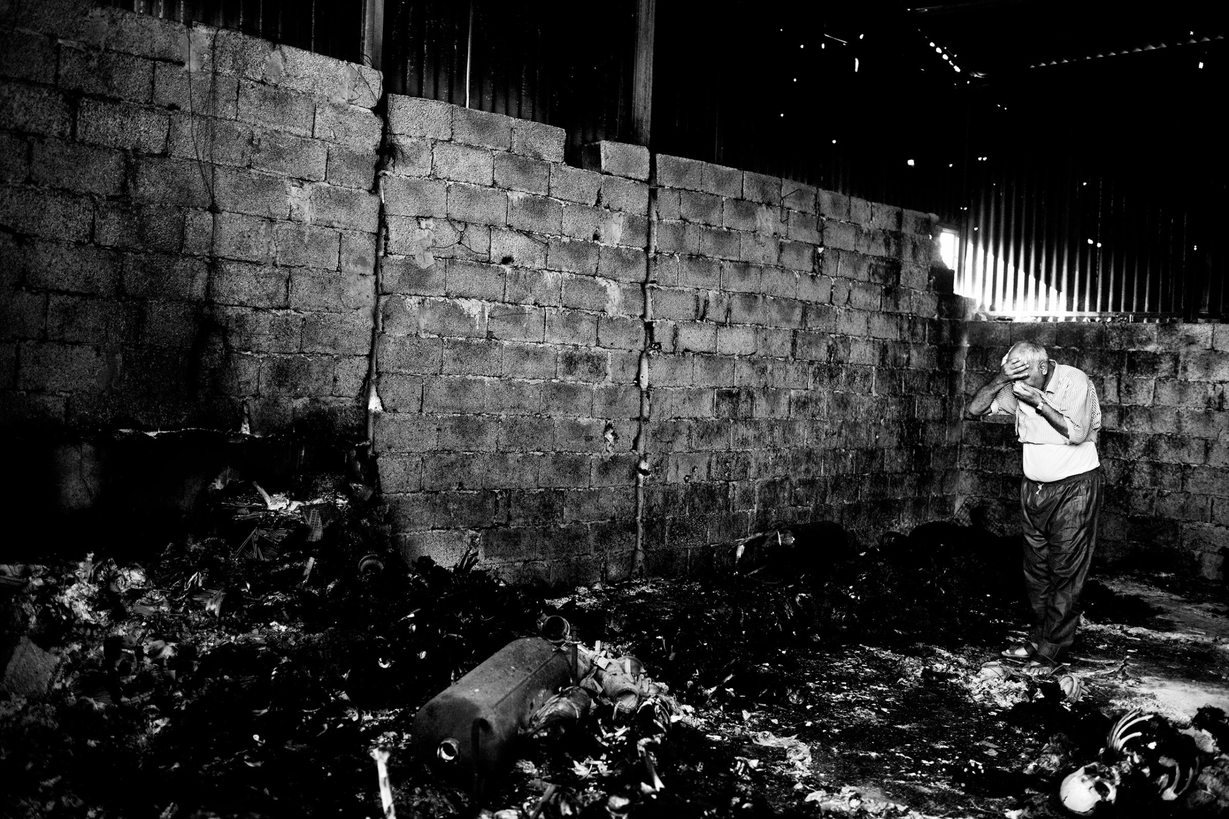 A libyan man despairs himself inside the warehouse which holds the remains of 50 burned bodies. Suburbs of Tripoli, Libya. August 27, 2011.