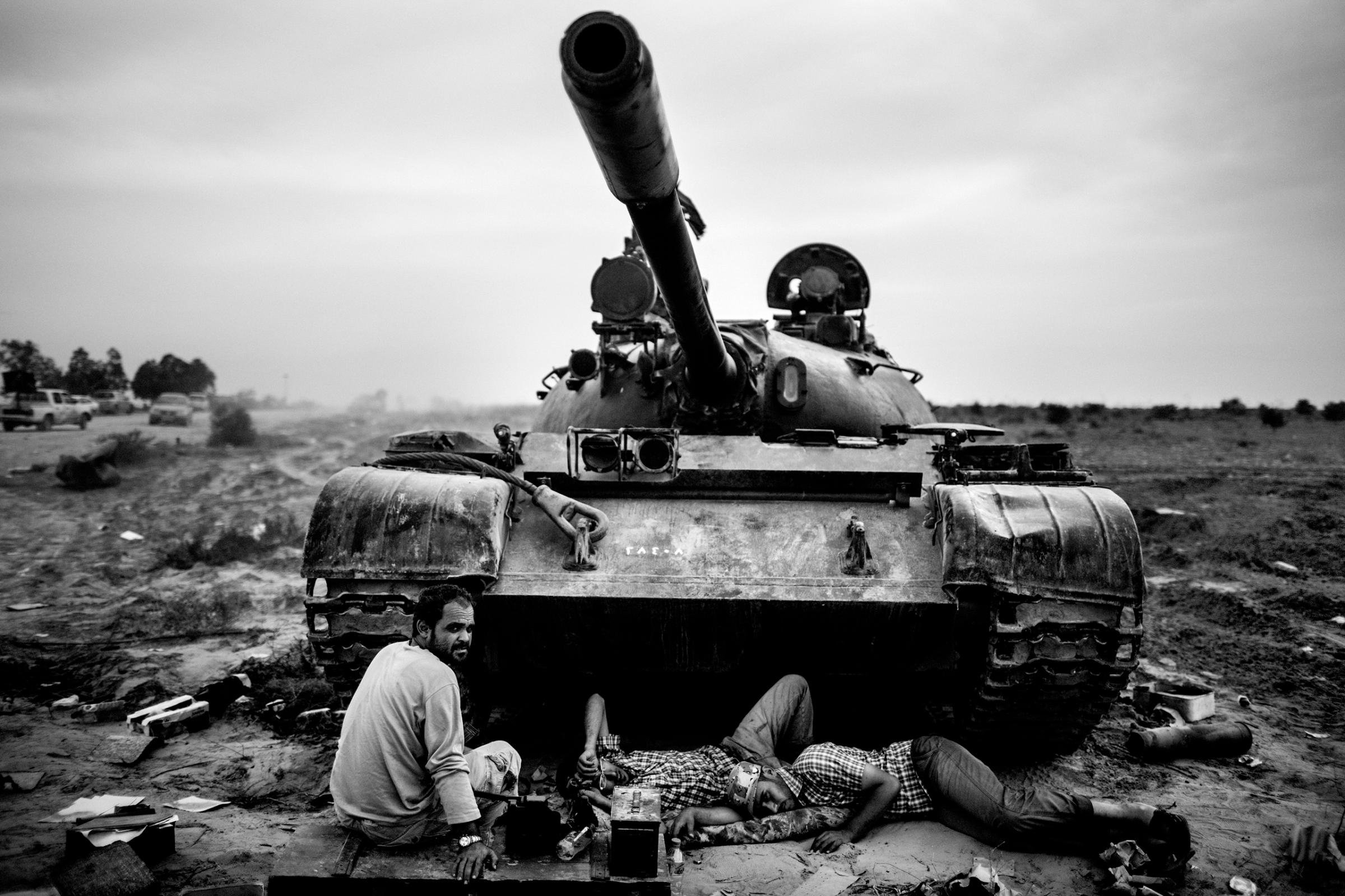 Revolutionary fighters rest near a tank during fighting for control of the Libyan city of Sirte, Oct.7, 2011.