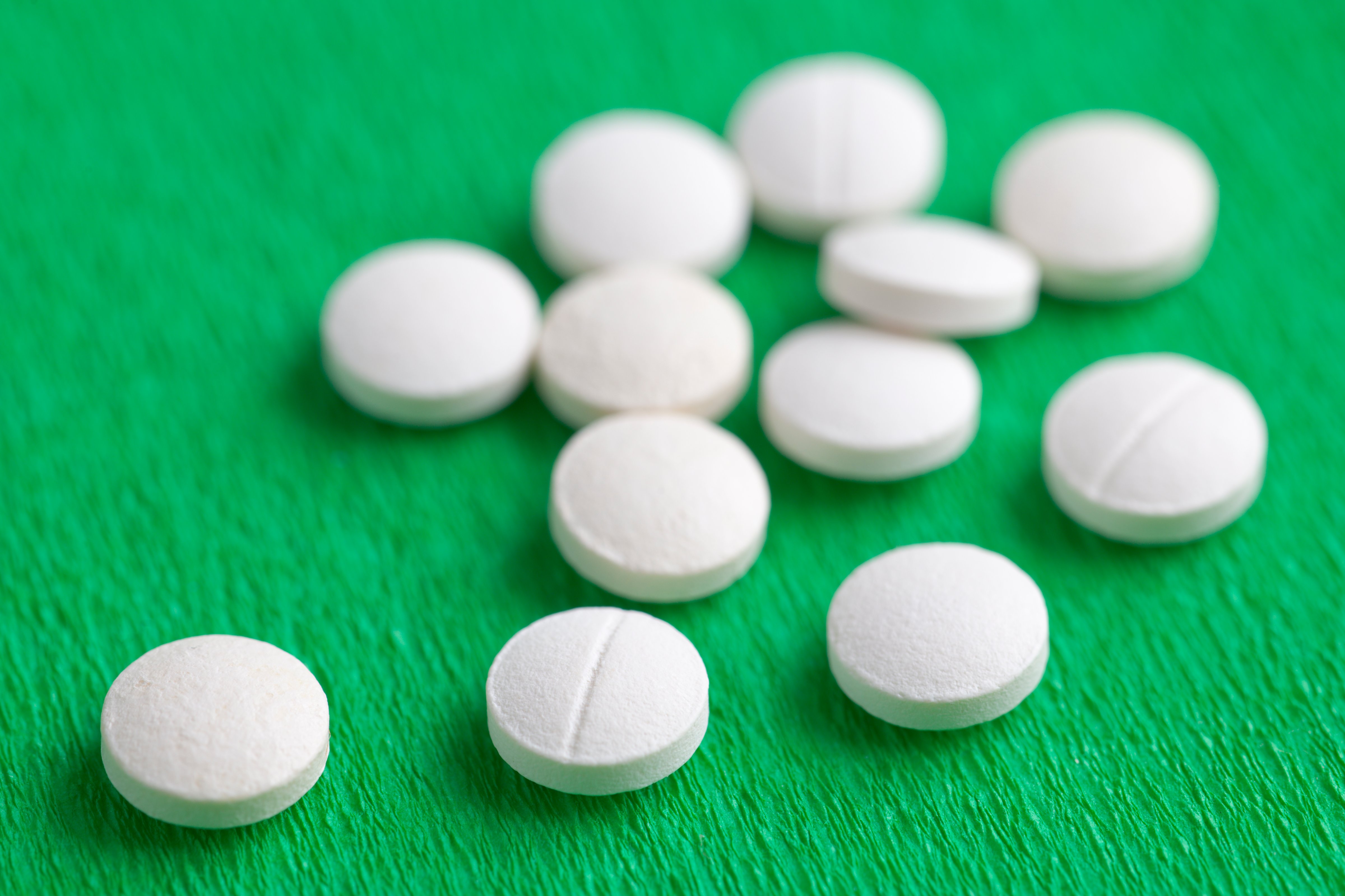 White Melatonin Natural Medicine Sleeping Pills on Green Backgro