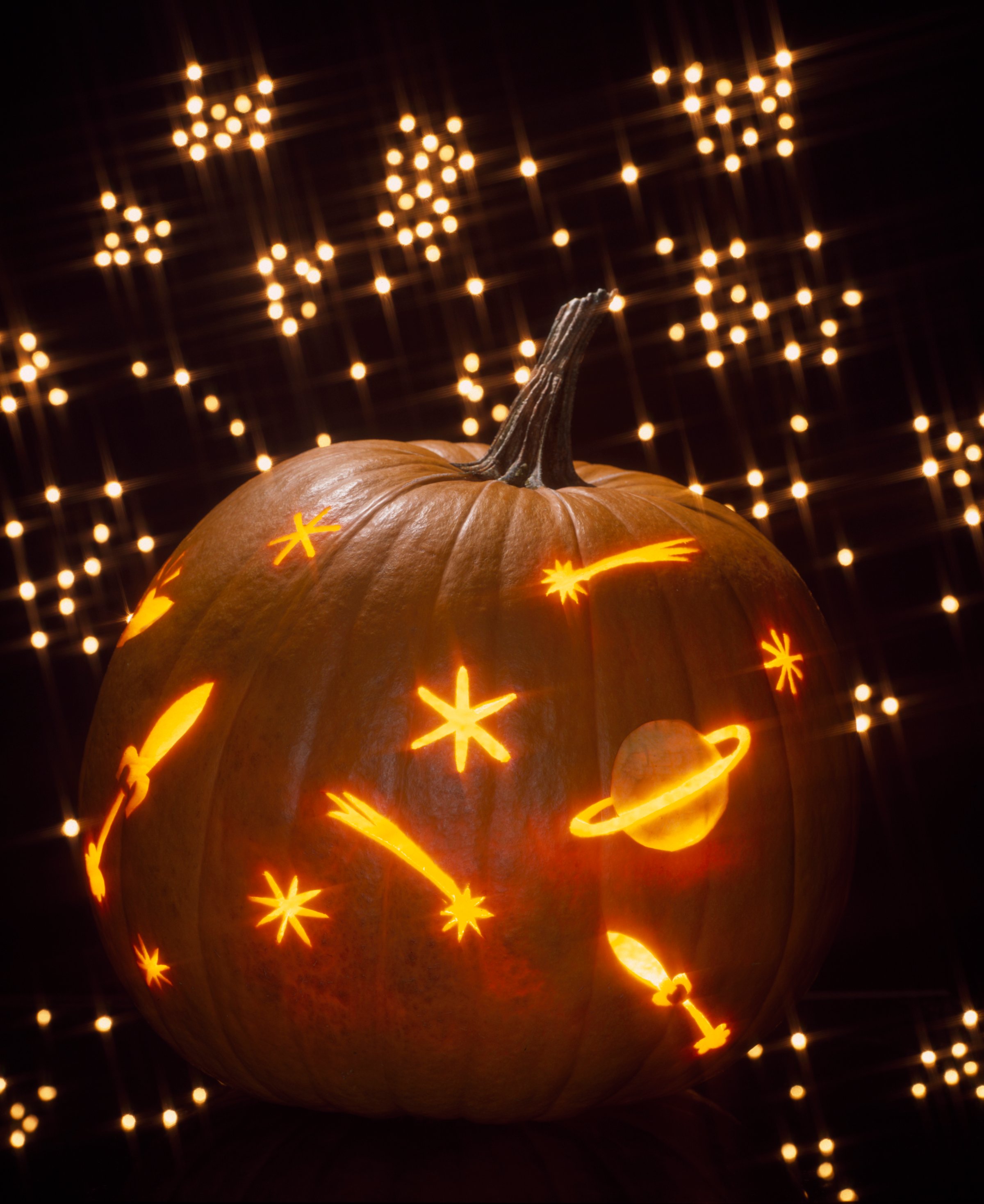 Pumpkin carved as a galaxy of shooting stars and planets