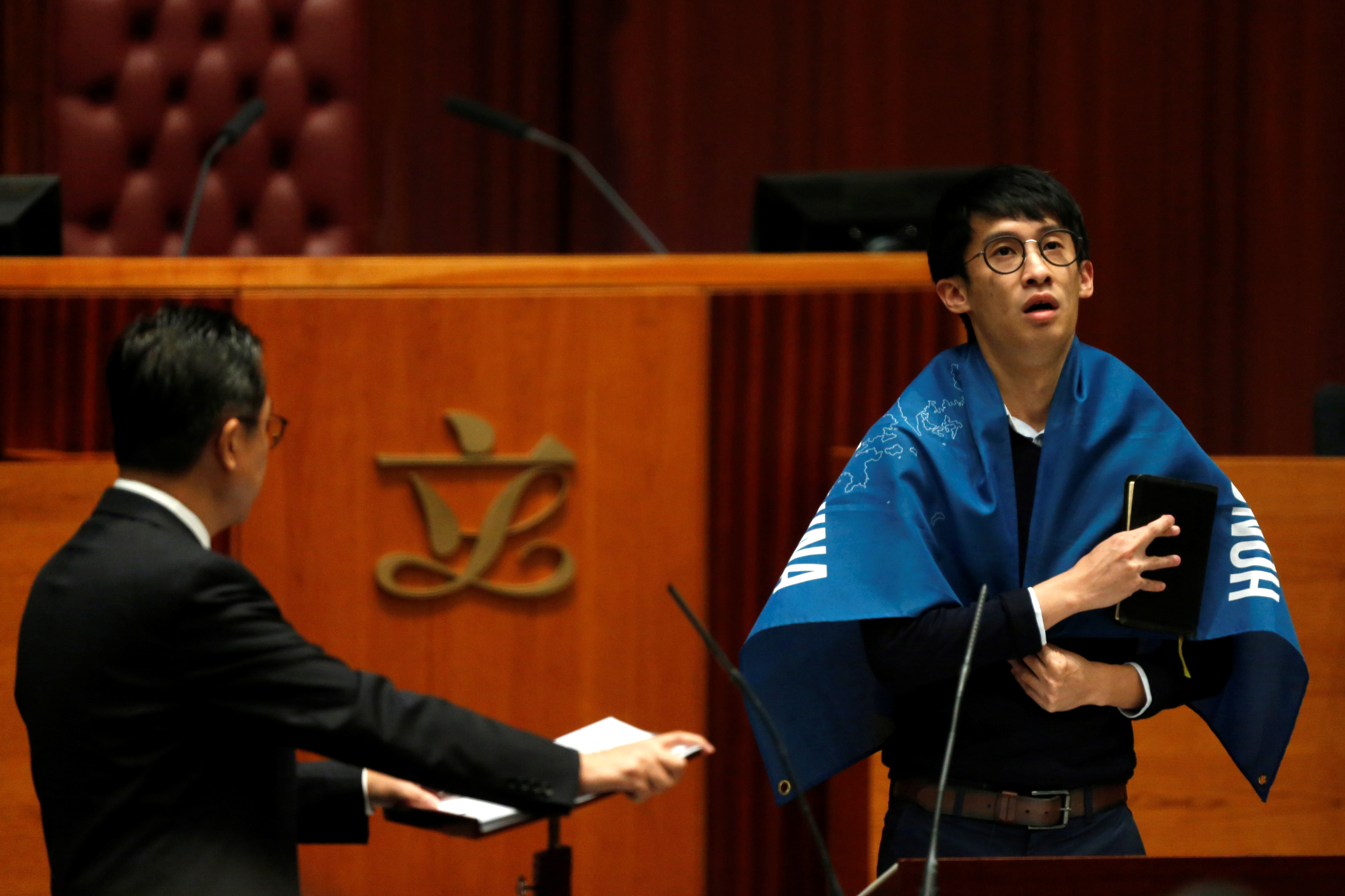 Newly elected lawmaker Baggio Leung wears a banner while taking oath at the Legislative Council in Hong Kong
