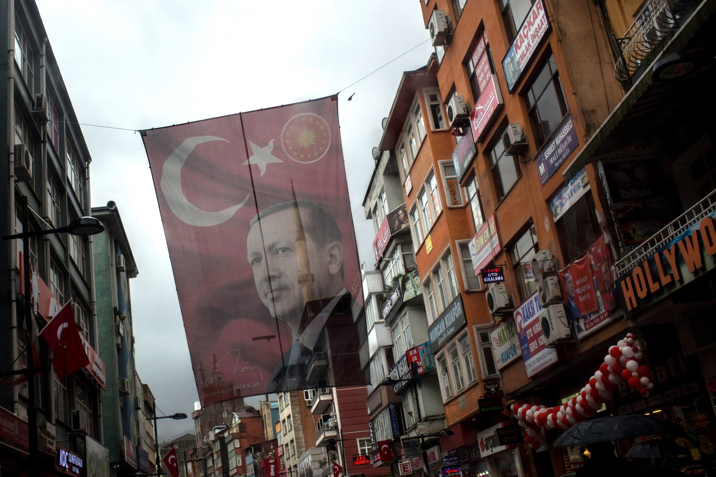 RIZE, TURKEY - OCTOBER 25: A large flag of Turkish president Recep Tayyip Erdogan is seen hanging over a main street on October 25, 2016 in Rize Turkey. Although born in Kasimpasa, Istanbul, President Erdogan's family was originally from Rize a conservative town on the Black Sea. His family returned to Rize when Erdogan was very young staying until he was 13, before returning to Istanbul. Since the failed coup attempt on July 15, 2016 which saw 240 people killed including 173 civilians, Turkish authorities initiated a state of emergency, leading to an unprecedented crackdown on individuals and organizations with links to US-based cleric Fethullah Gulen and his organization blamed for instigating the uprising. The purge, targeting teachers, journalists, soldiers, judges, academics, police, military leaders, schools and universities has so far seen approximately 100,000 people dismissed, 70,000 detained, 32,000 arrested, 130 media outlets closed and some 15 universities shuttered. The failed coup and subsequent purge only appears to have further bolstered the president's popularity and increased nationalism across the country with July 15th having been marked as a new national holiday. Turkish flags, already prominently displaying all over have increased in numbers, as well as posters of those killed fighting the coup plotters appearing in train stations and public squares. The Bosphorus Bridge in Istanbul, which saw heavy fighting during the coup has been renamed the '15th July Martyr's Bridge'. These changes, follow a year of instability in the country with constant terrorist attacks, an economic downturn, plummeting tourism, and a refugee crisis, all contributing to Turkish society undergoing its most dramatic restructuring in decades. (Photo by Chris McGrath/Getty Images)