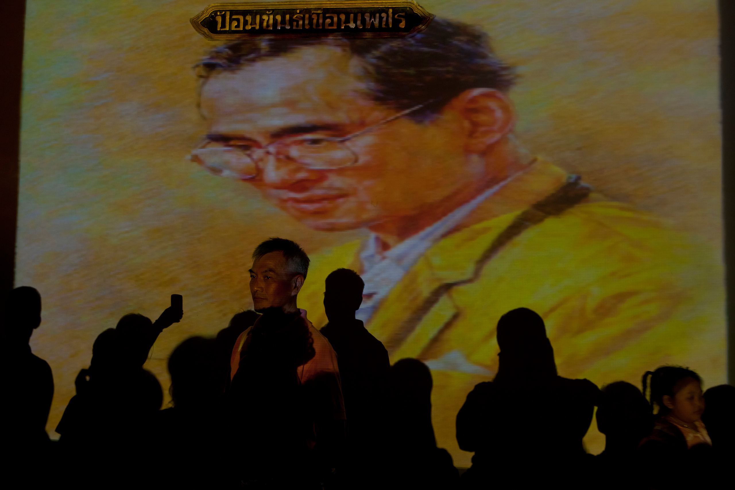 People in front of an image of King Bhumibol Adulyadej of Thailand during a celebration of his 84th birthday, Bangkok, Thailand, Dec. 5, 2011.