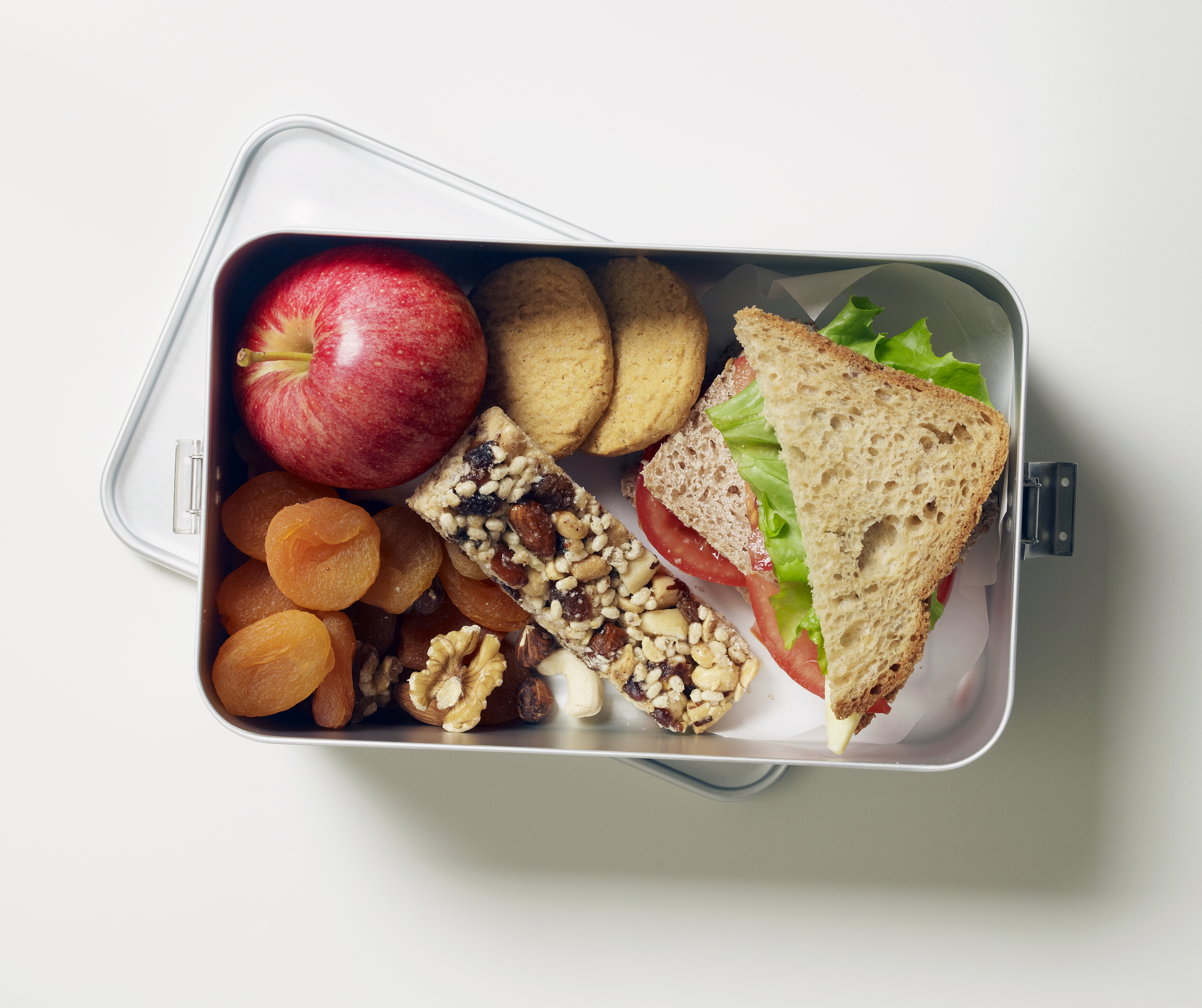 Gluten-free lunch box containing fruit, seed bar, biscuits and sandwiches